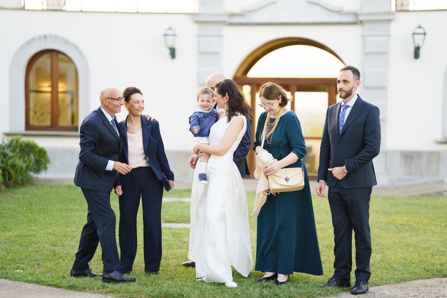 Casual interactions between wedding party members outside white church building.