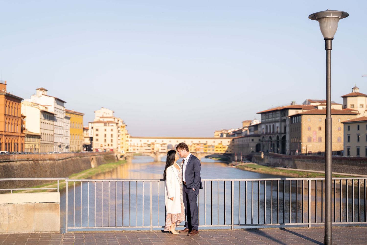 A scenic view of the Arno River in Florence, Italy with historic buildings and bridges along the riverbank.