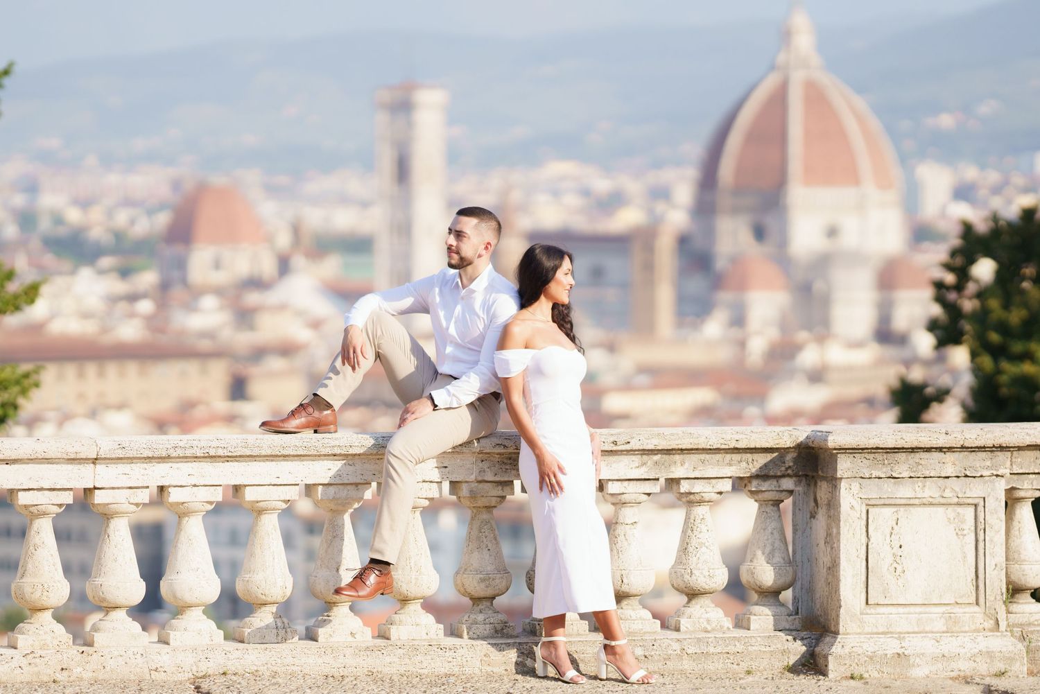 Couple shares romantic moment overlooking Florence cityscape with iconic Duomo cathedral in background.