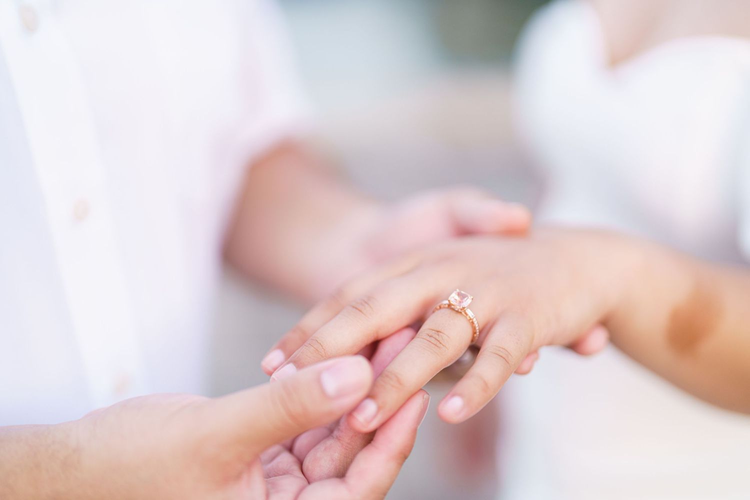 A close-up of hands gently holding and caressing each other in a loving gesture against a soft blurred background.