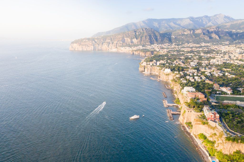 Aerial panorama of the dramatic Amalfi Coast with luxury villas perched on cliffs above the Mediterranean.