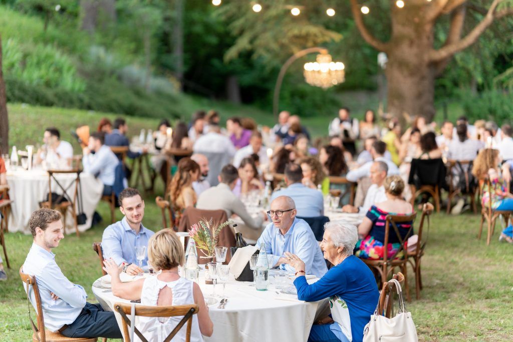 Garden wedding reception with string lights and guests dining at long tables.
