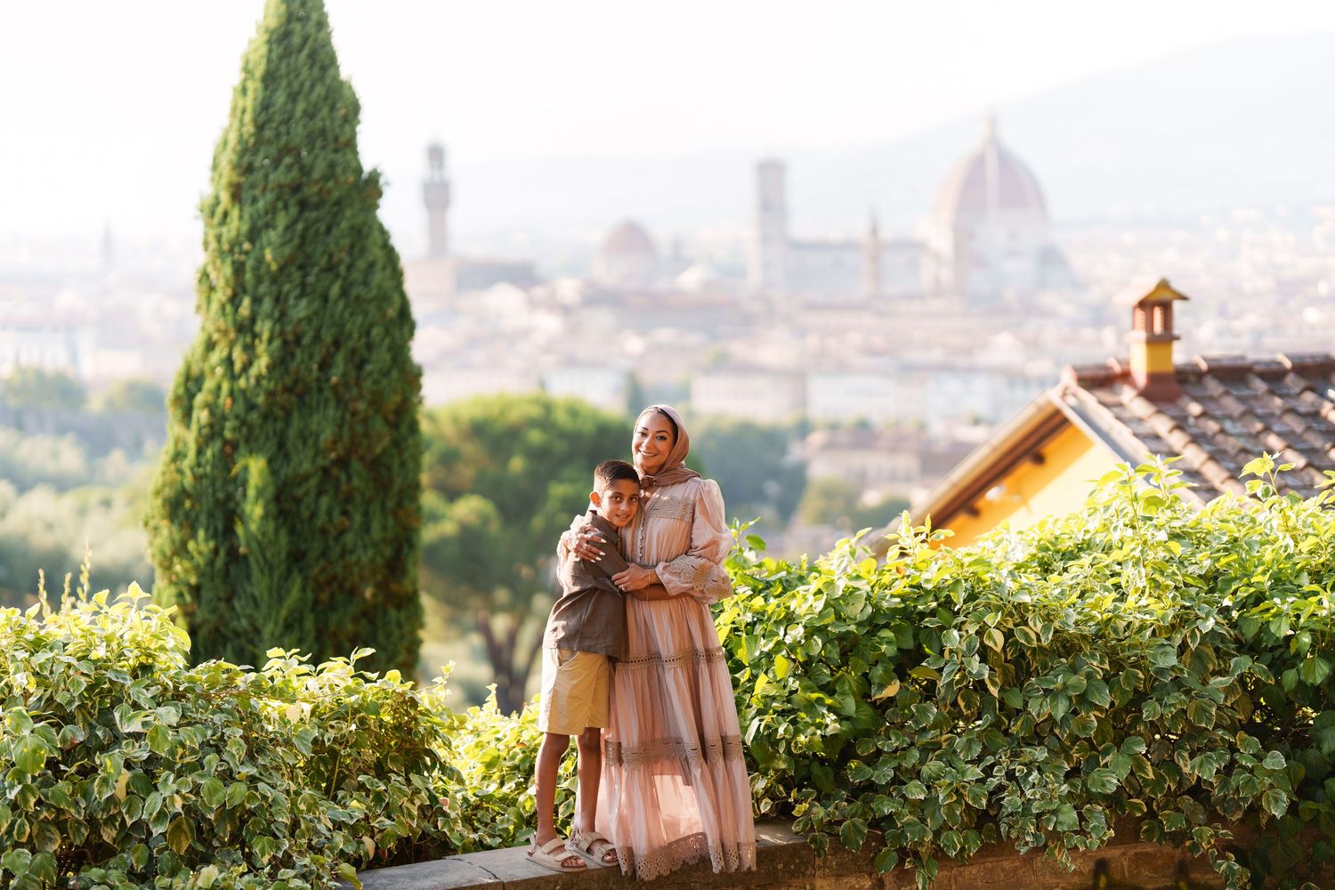 Mother and child embrace on a terrace overlooking Florence skyline with the Duomo in the background.