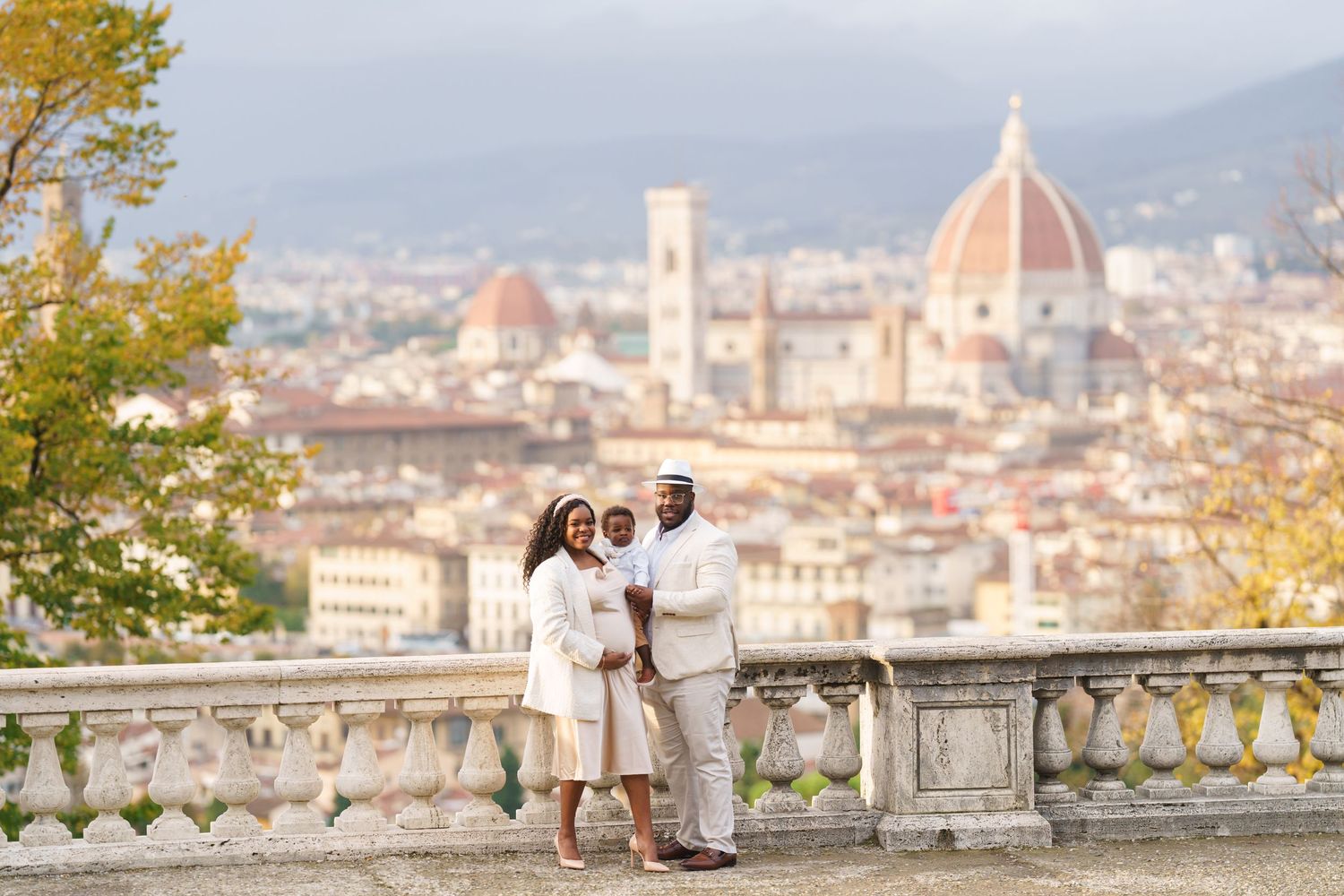Family in white poses on Florence terrace with Duomo cathedral and city skyline backdrop.