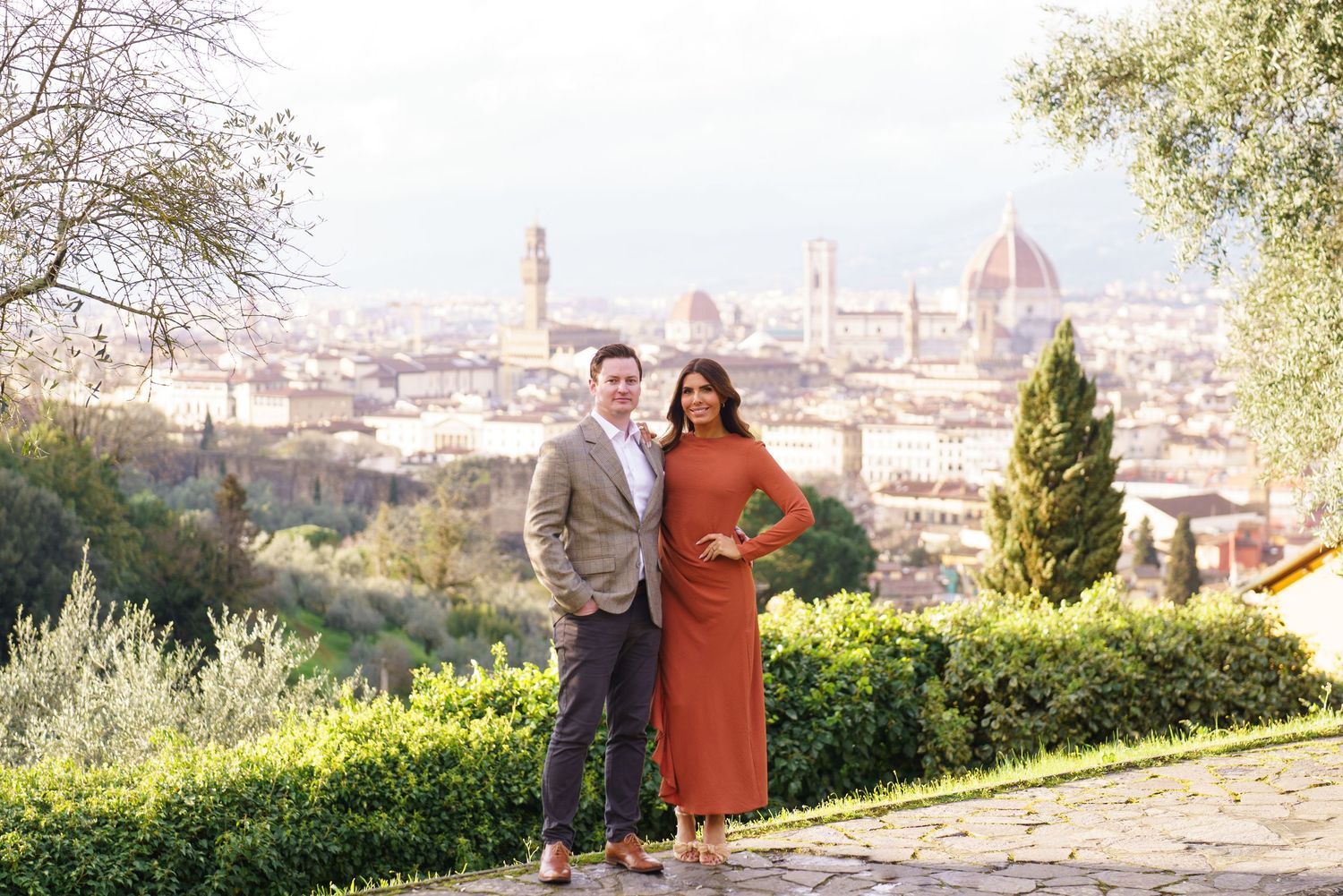 Couple posing together on a scenic overlook with the Florence skyline and cathedral dome in the background.