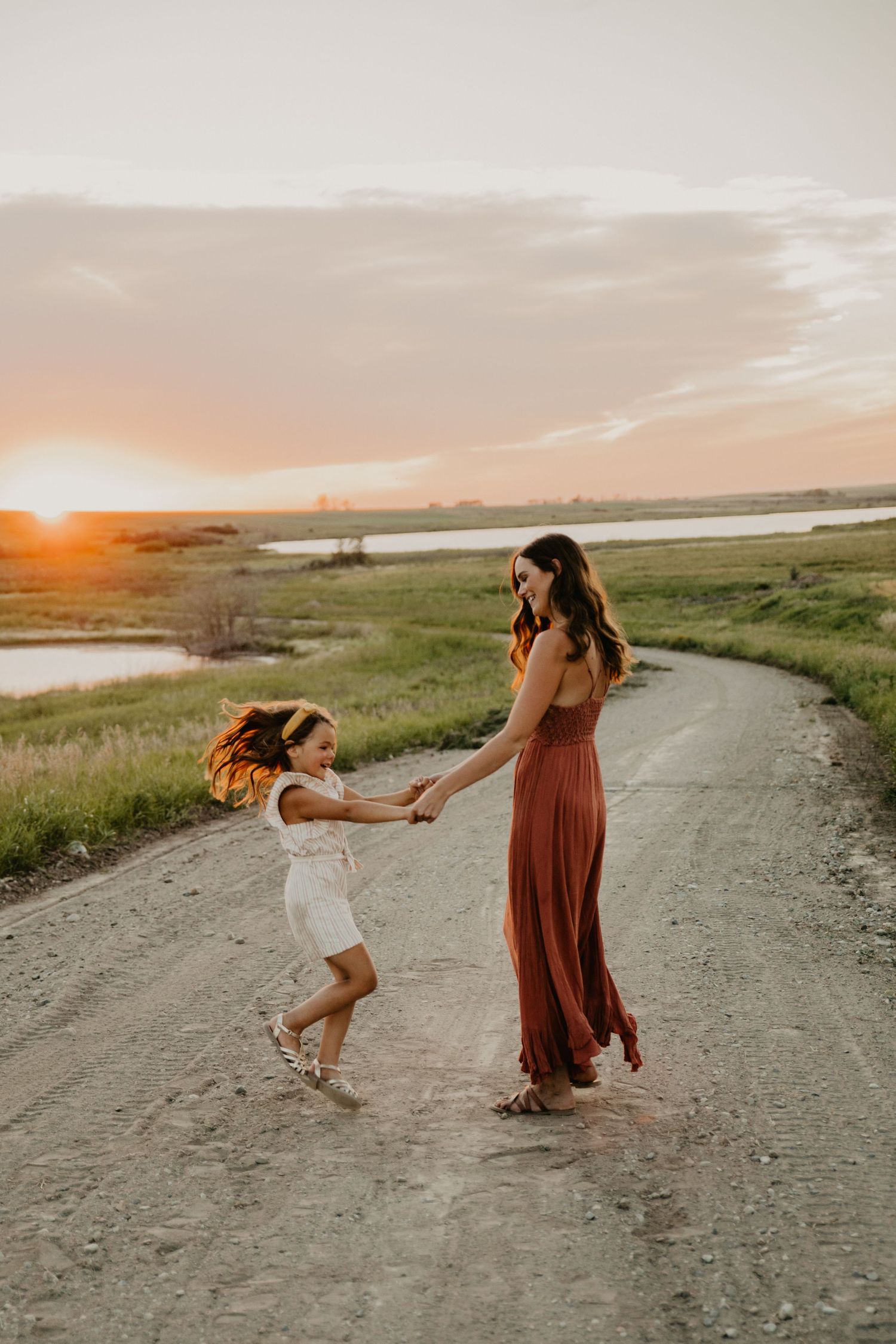 A playful dance moment on a dirt path with sunset glowing over the lake.