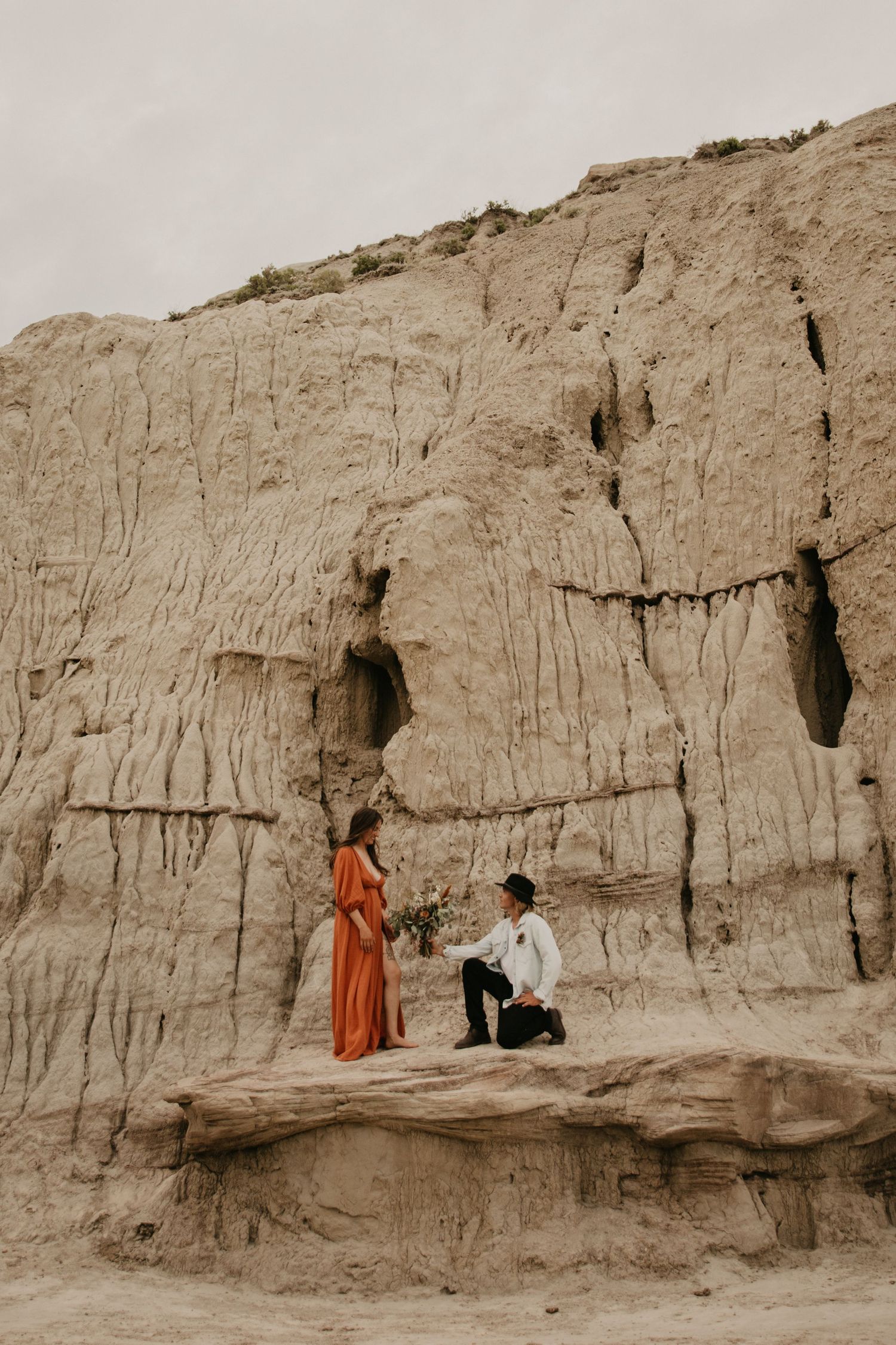 A special moment captured against dramatic clay cliffs as a couple shares an intimate scene.