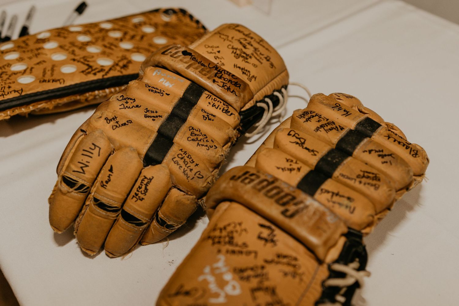 Brown leather gloves covered in handwritten messages and signatures.
