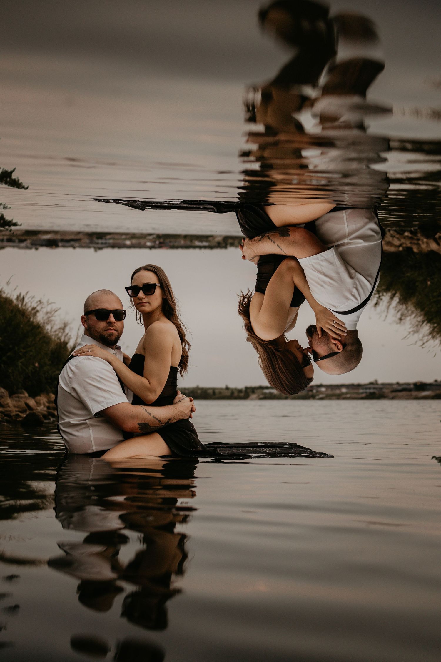Creative water reflection portrait at sunset showing couple in still lake.