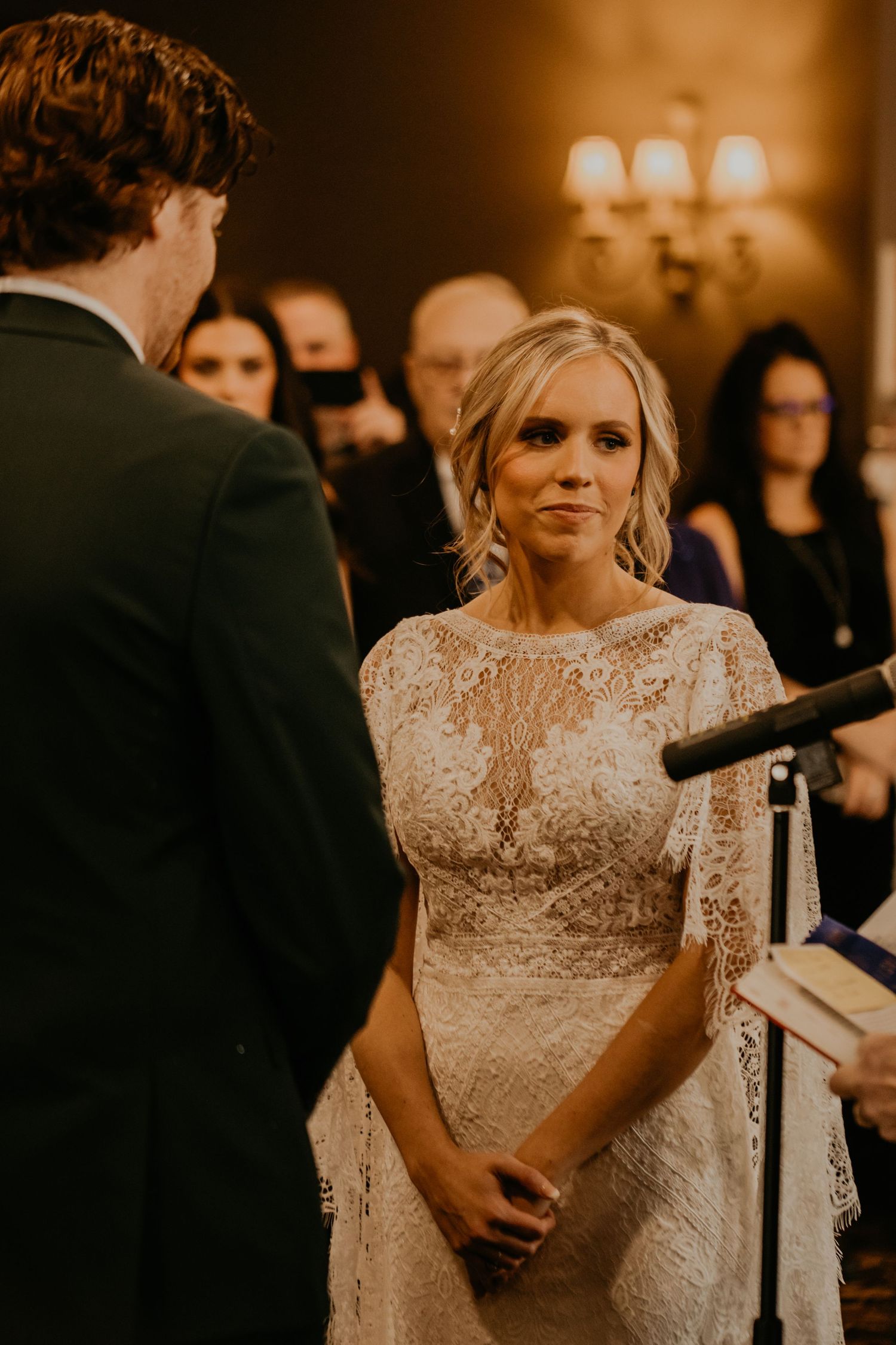 Indoor wedding ceremony with couple exchanging vows in warm lighting.
