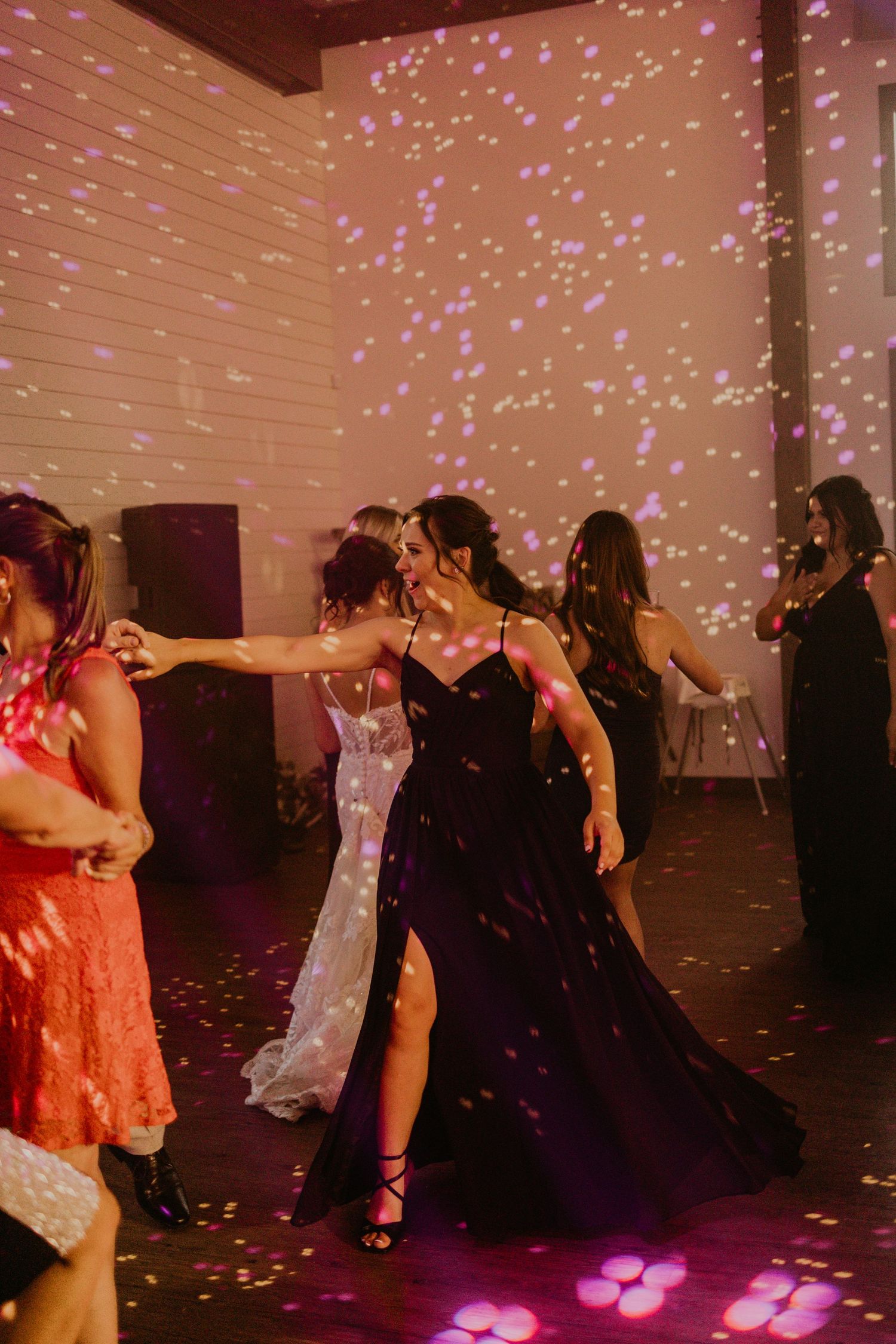 Wedding reception dance party with glittering lights and guests dancing in formal attire.