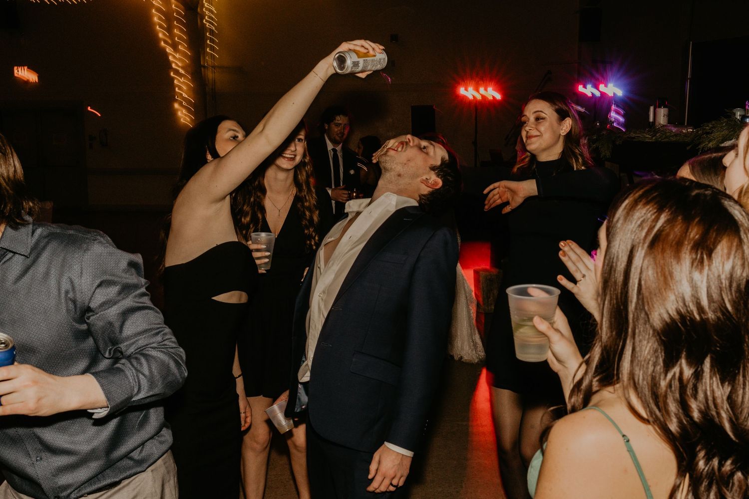 Wedding reception guests dancing energetically under colorful party lights.