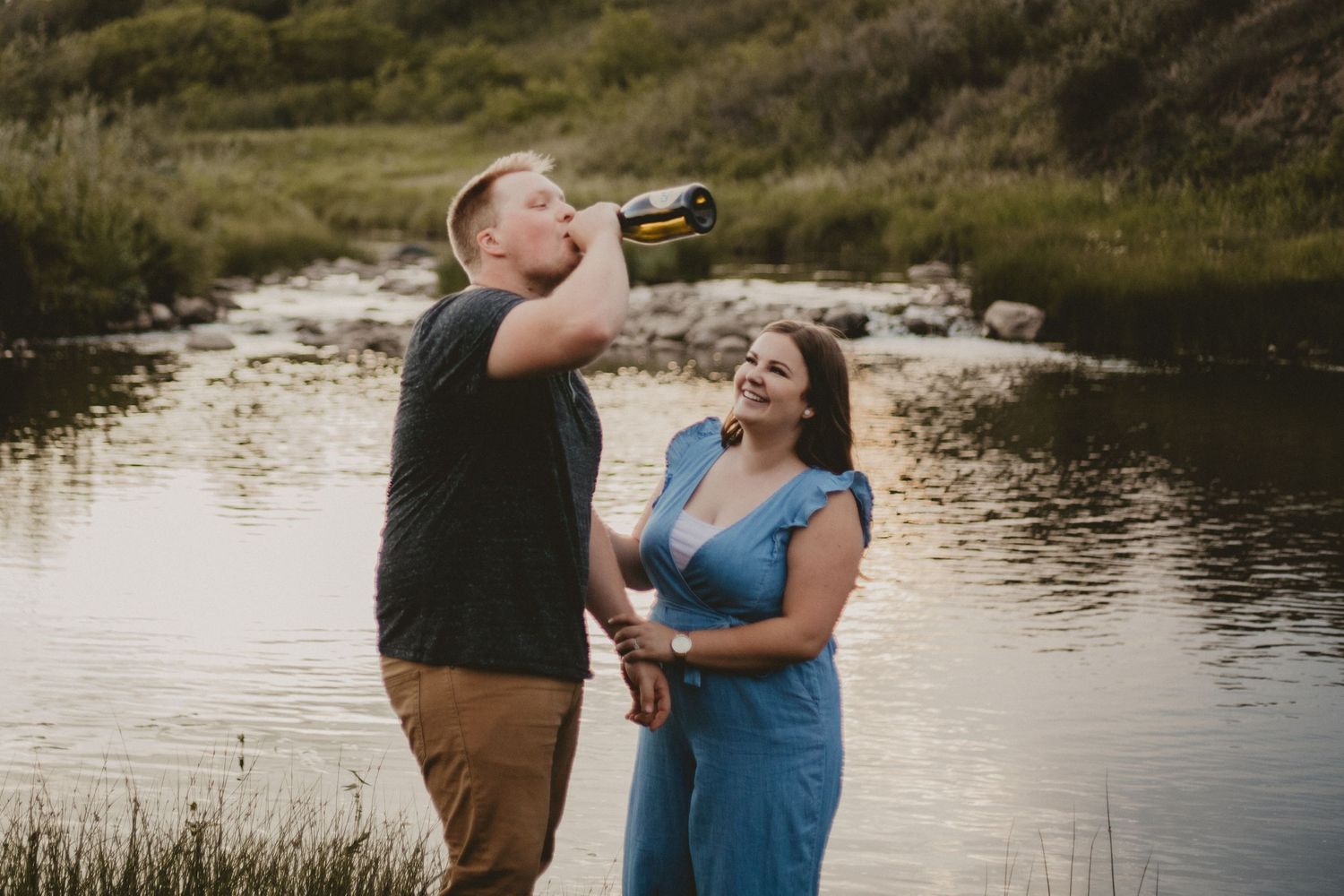 A couple enjoying drinks by a serene lake during a casual outdoor moment.
