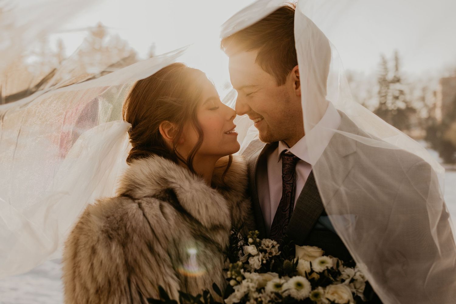 Winter wedding portrait with fur coat and veil in soft natural light.