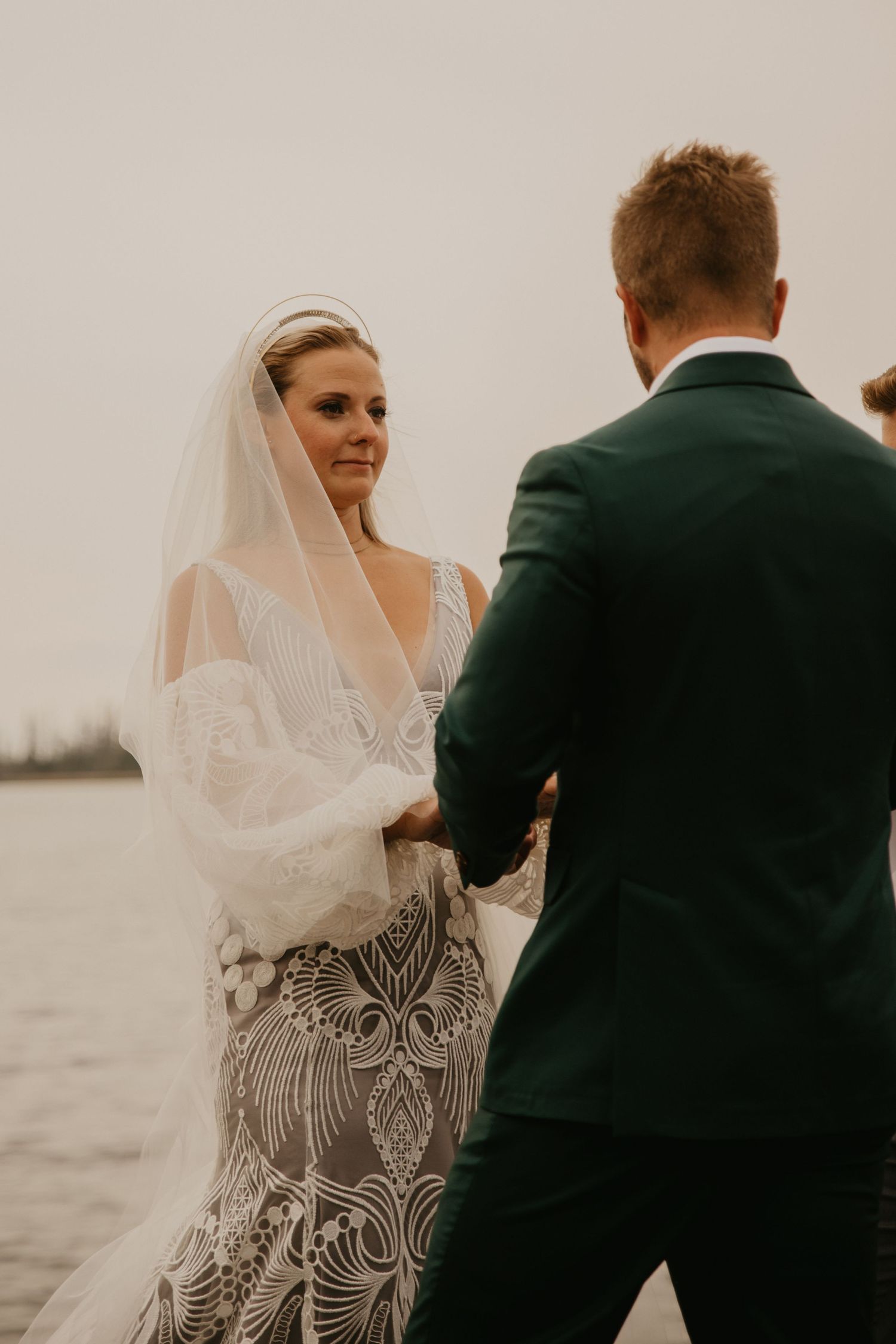 Intimate wedding ceremony moment at lakeside with overcast sky.