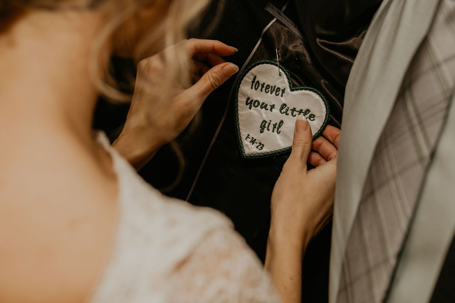Close-up of hands holding a small heart-shaped note attached to clothing.