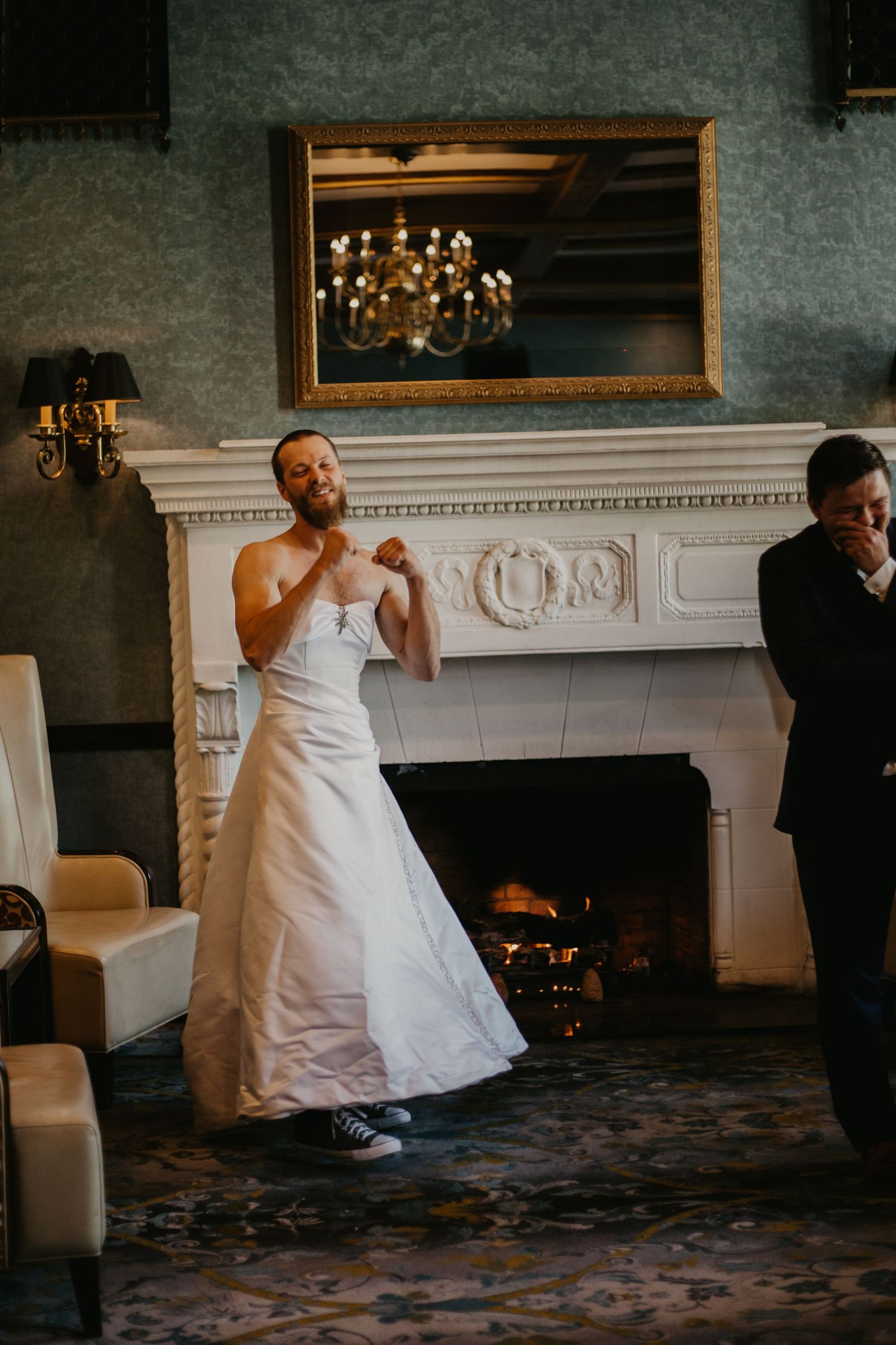 A wedding scene in an elegant room with a white fireplace, ornate mirror, and chandelier reflection.