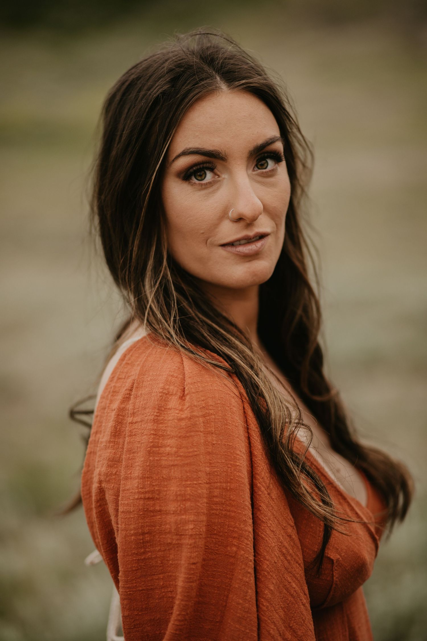 Portrait of someone wearing a rustic orange sweater against a nature backdrop.