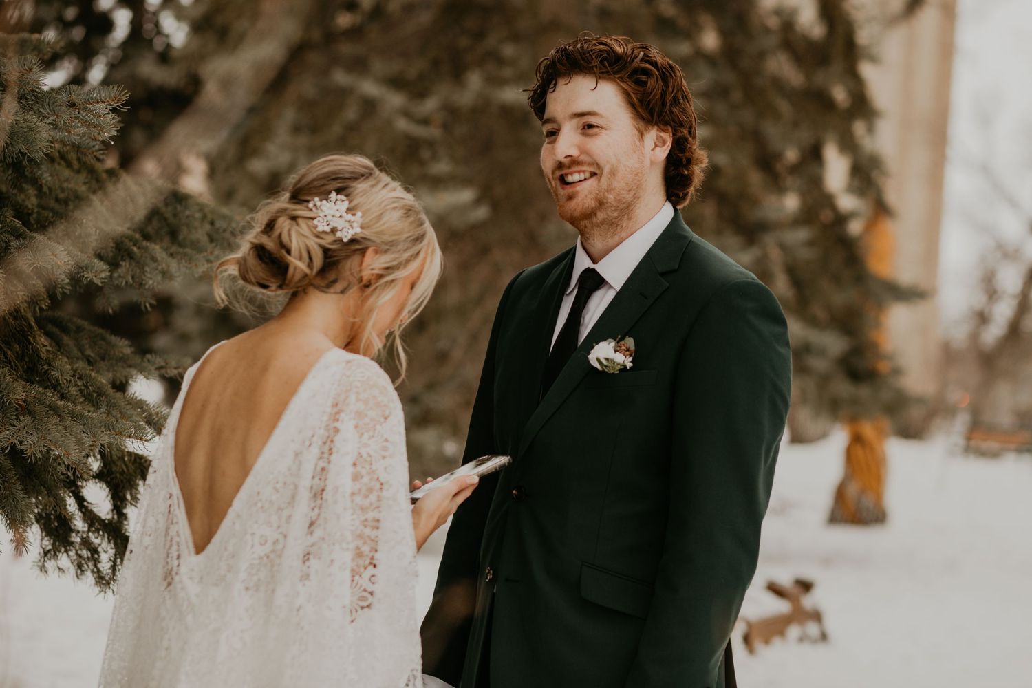 A romantic winter wedding exchange between a couple against a snowy backdrop.