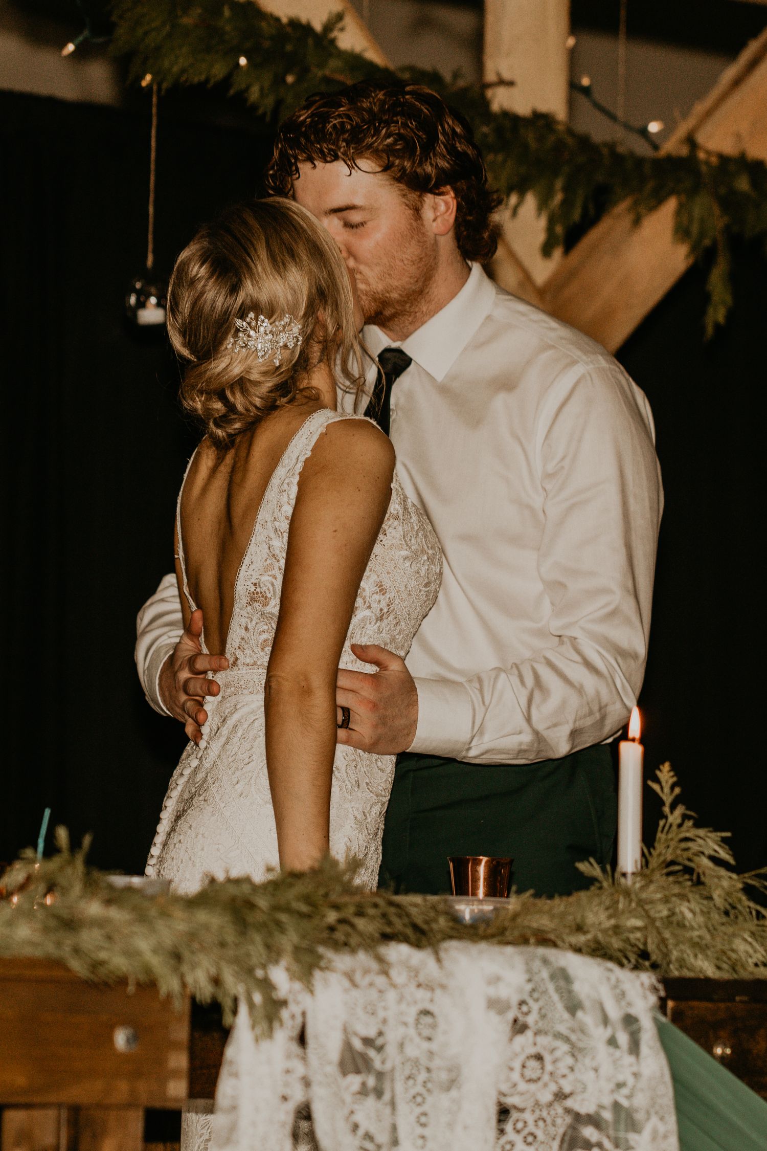 Intimate dance moment at wedding reception with lace dress and greenery decor.