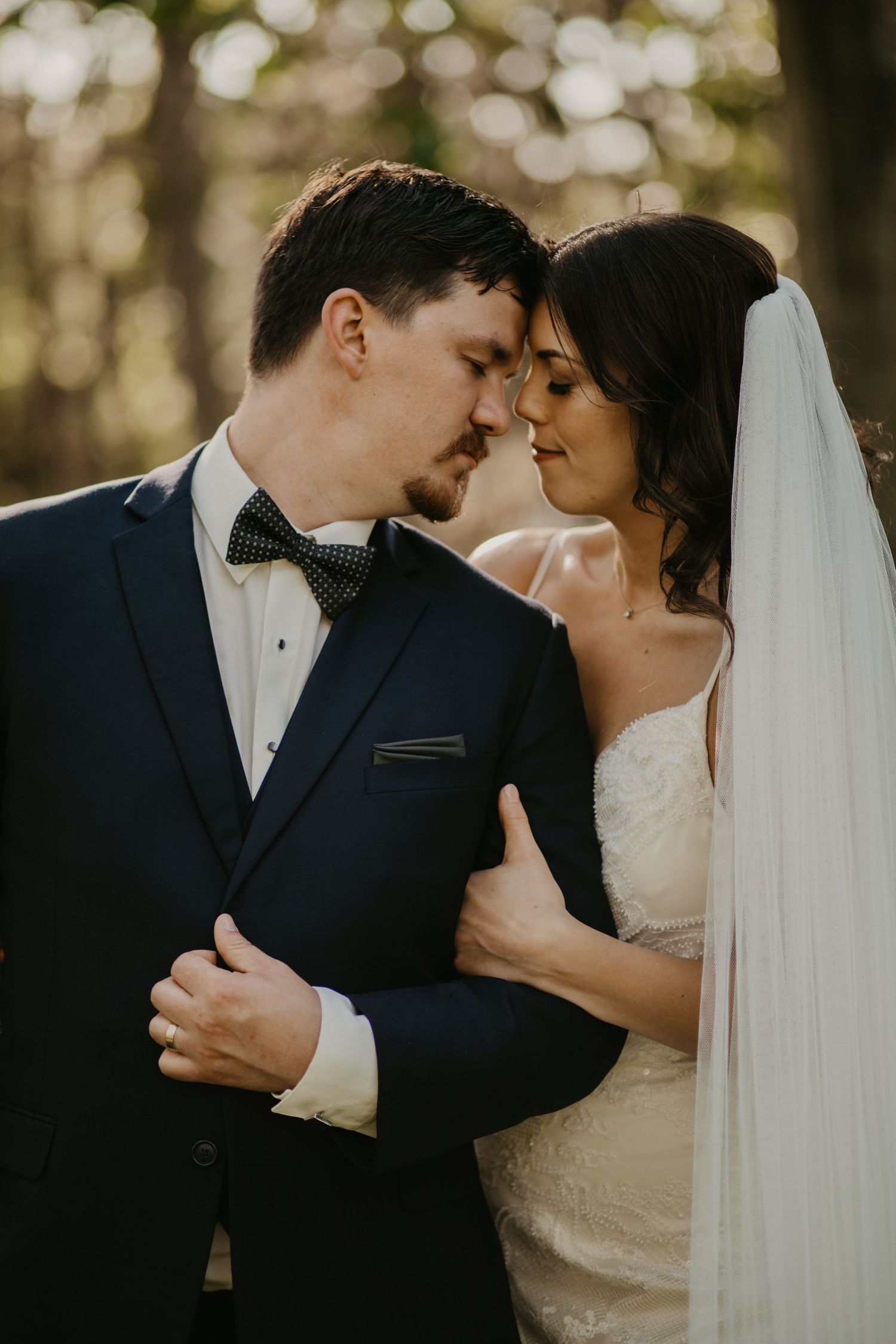 An intimate wedding portrait capturing a tender moment between newlyweds in golden hour lighting.