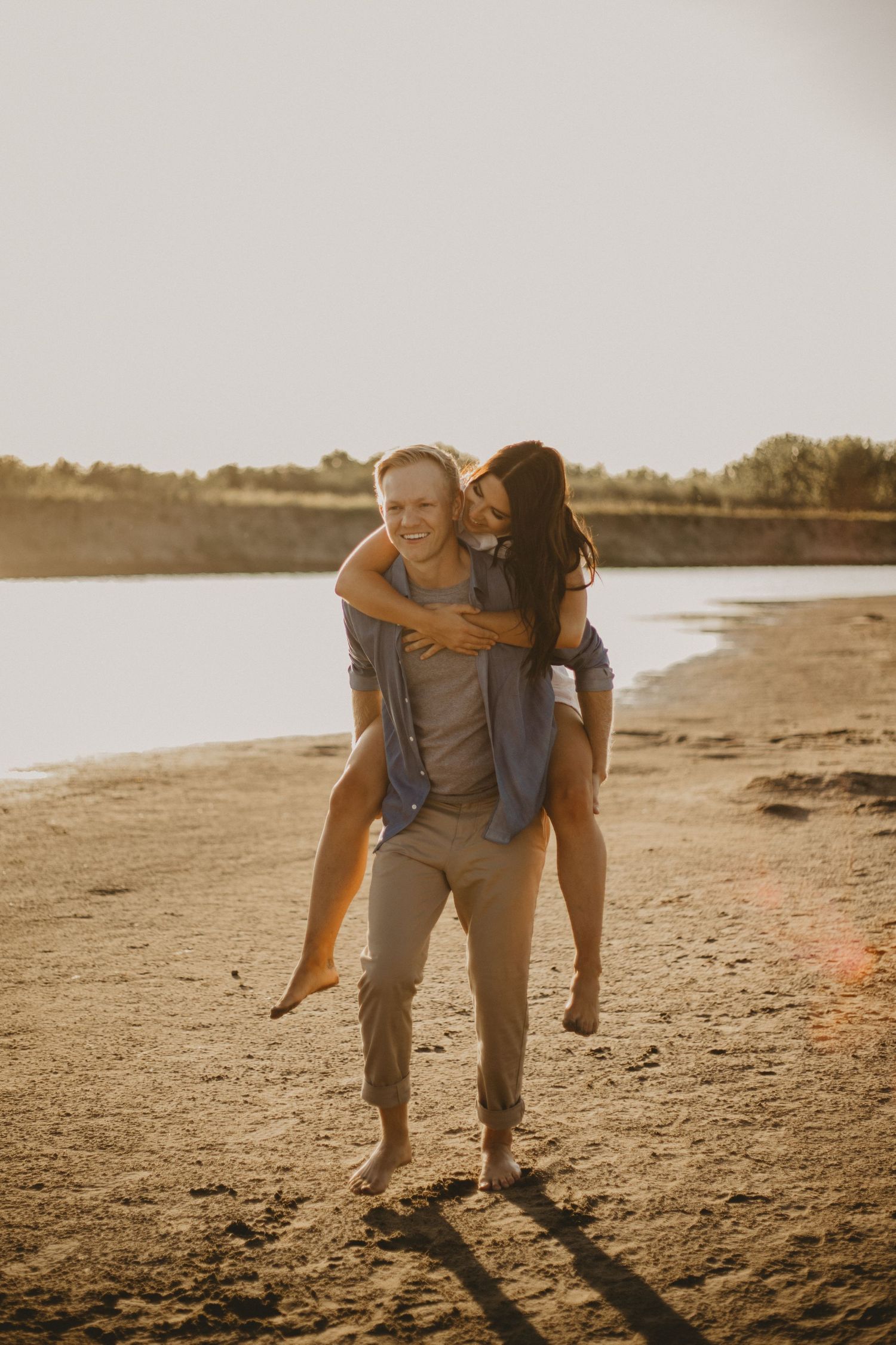 Playful piggyback ride on sandy beach during golden hour.