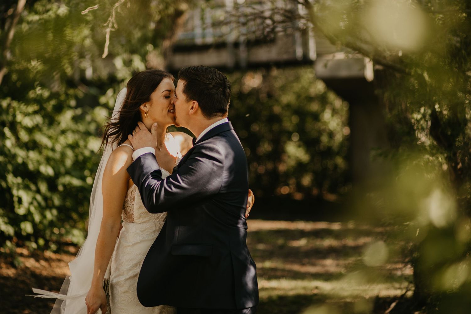 Intimate wedding moment captured in a lush garden setting with natural sunlight.