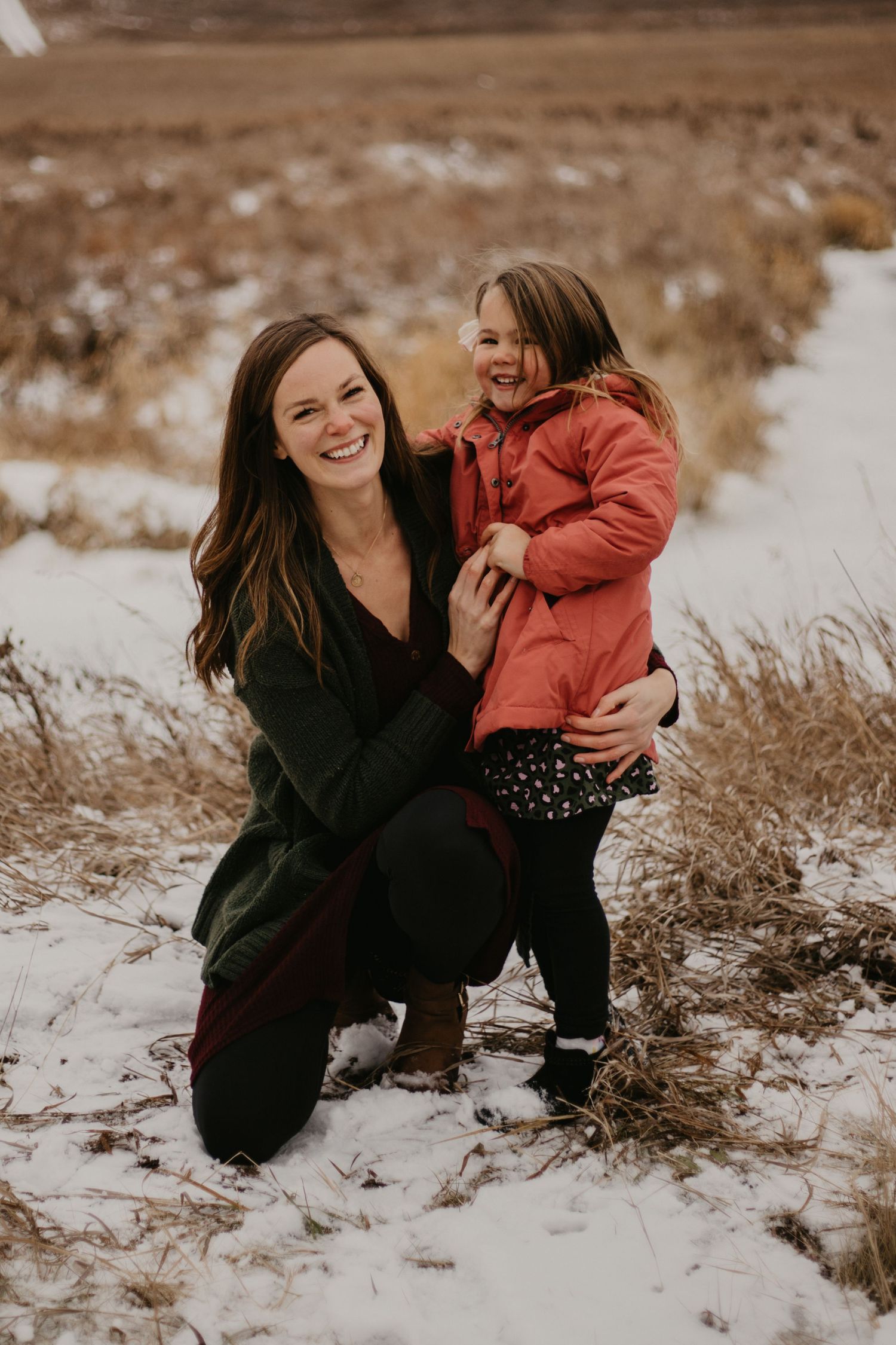 A loving moment captured between two people on a snowy winter day with natural scenery.