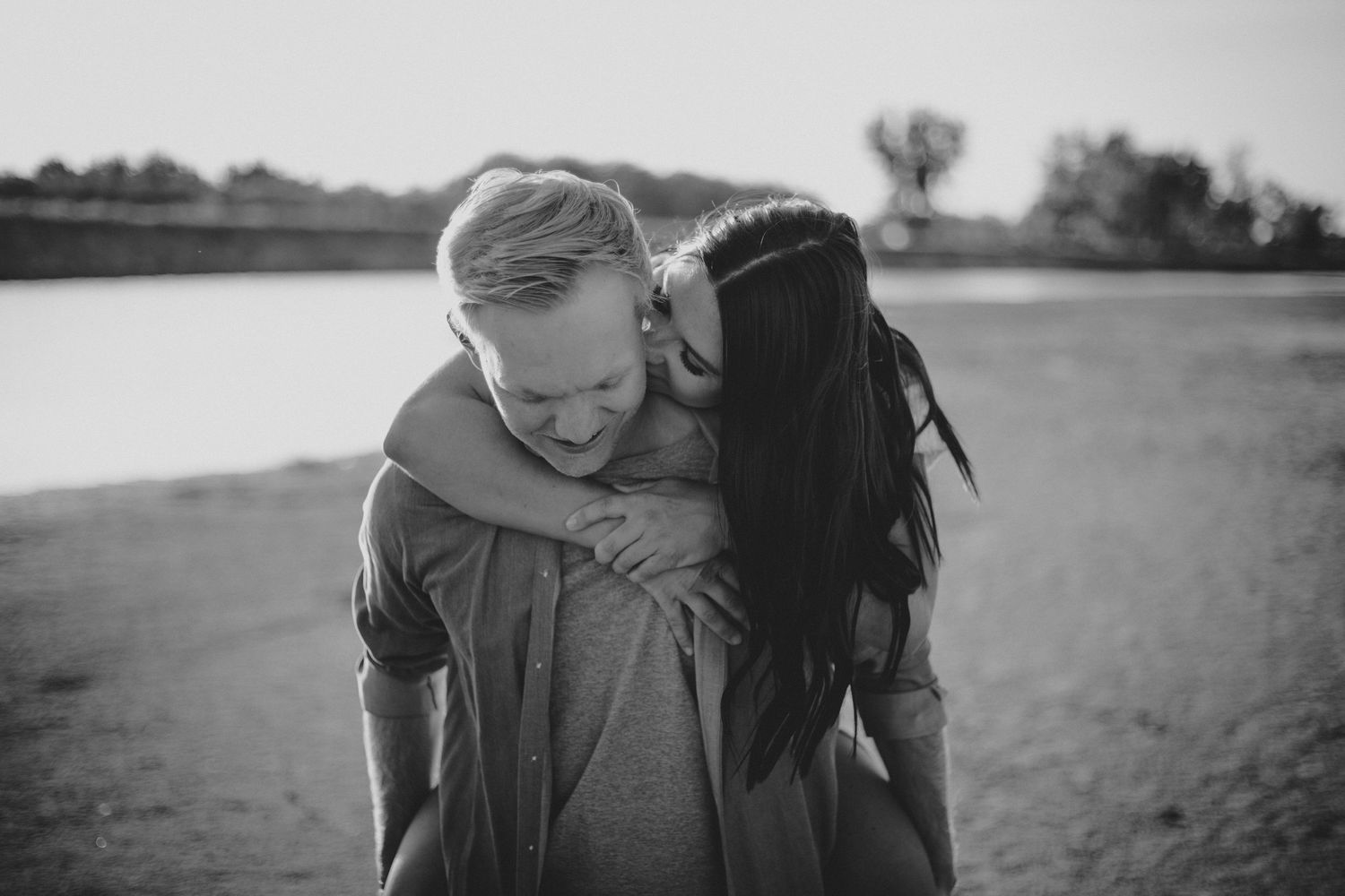 Black and white portrait of couple sharing intimate embrace outdoors.