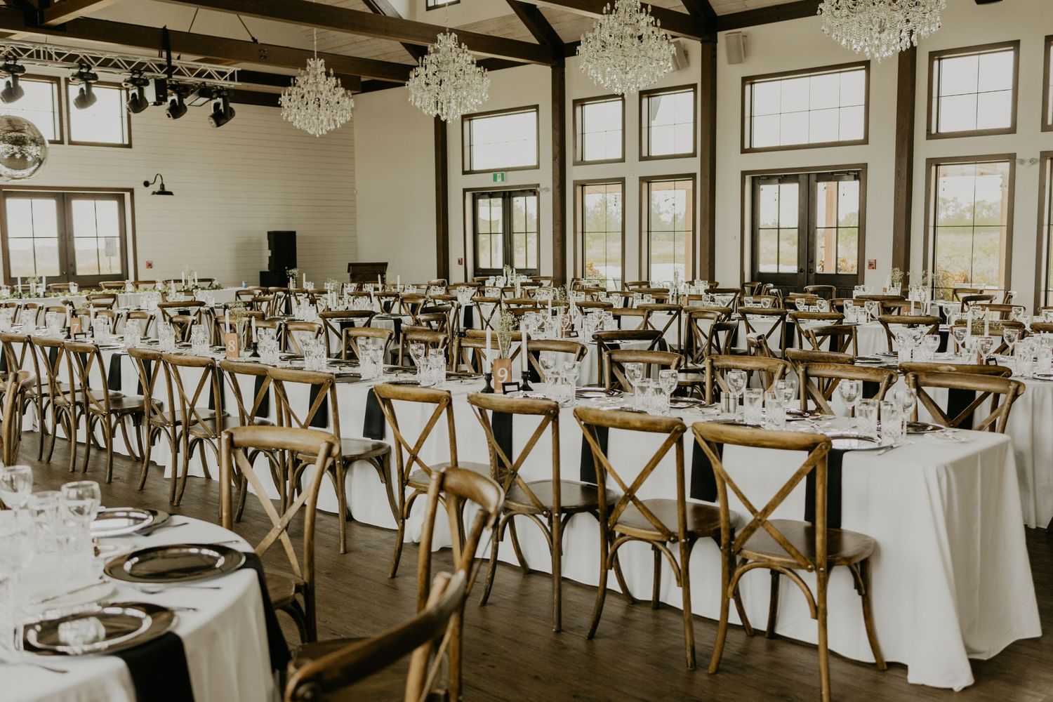 Elegant wedding reception venue with cross-back chairs and white table settings.