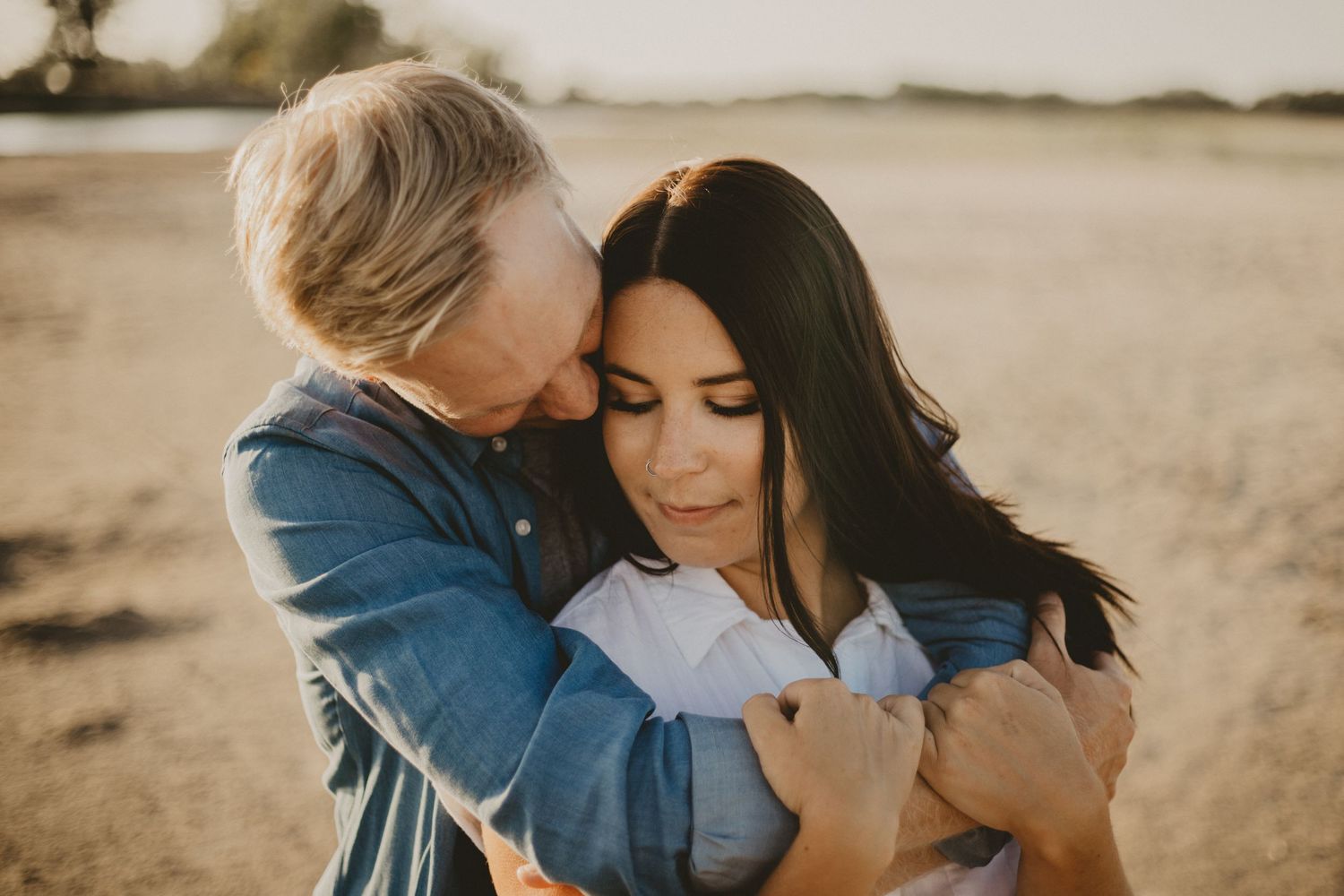 Intimate couple shares tender moment during sunset beach photoshoot.