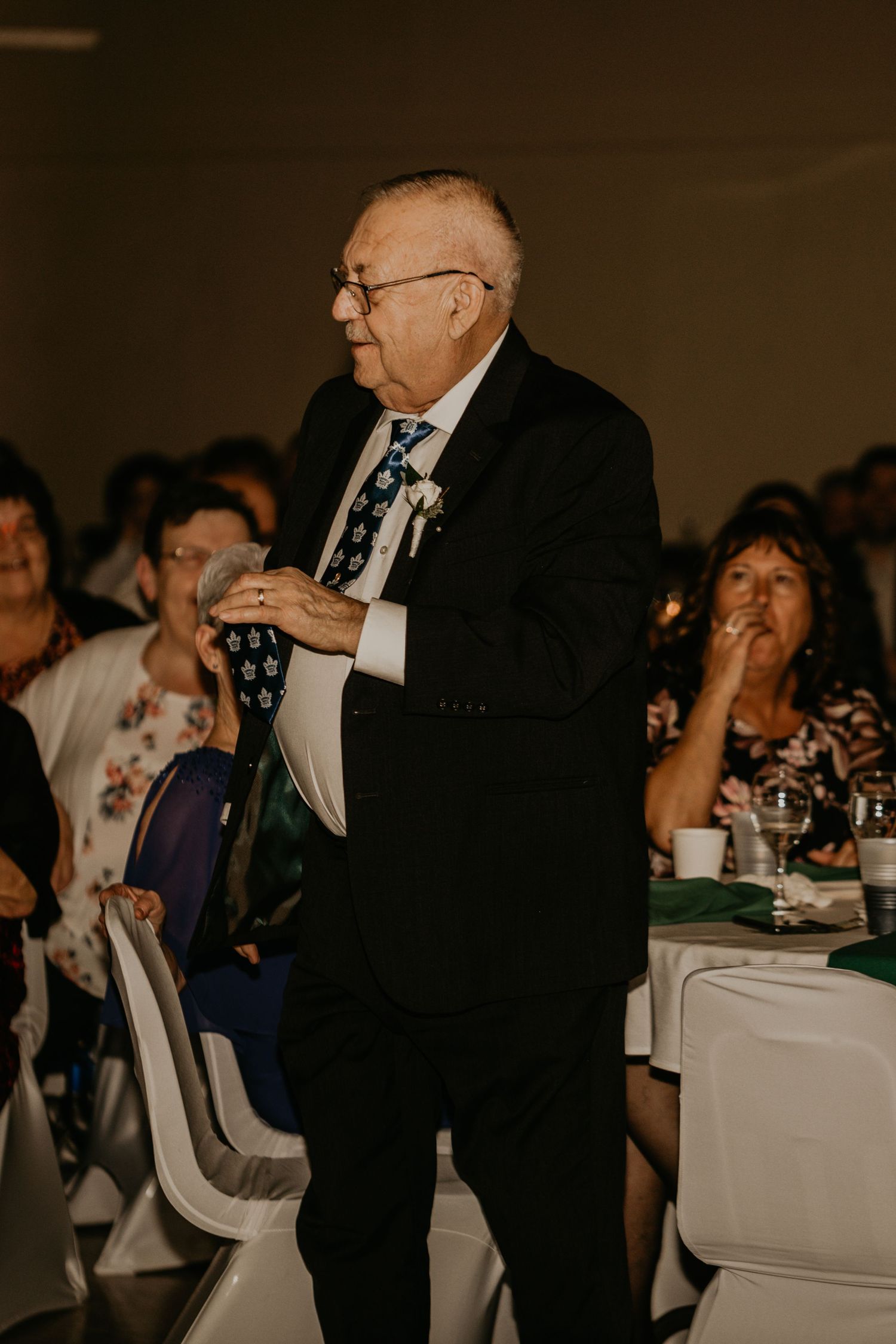 Formal reception speech by gentleman in black suit and tie.