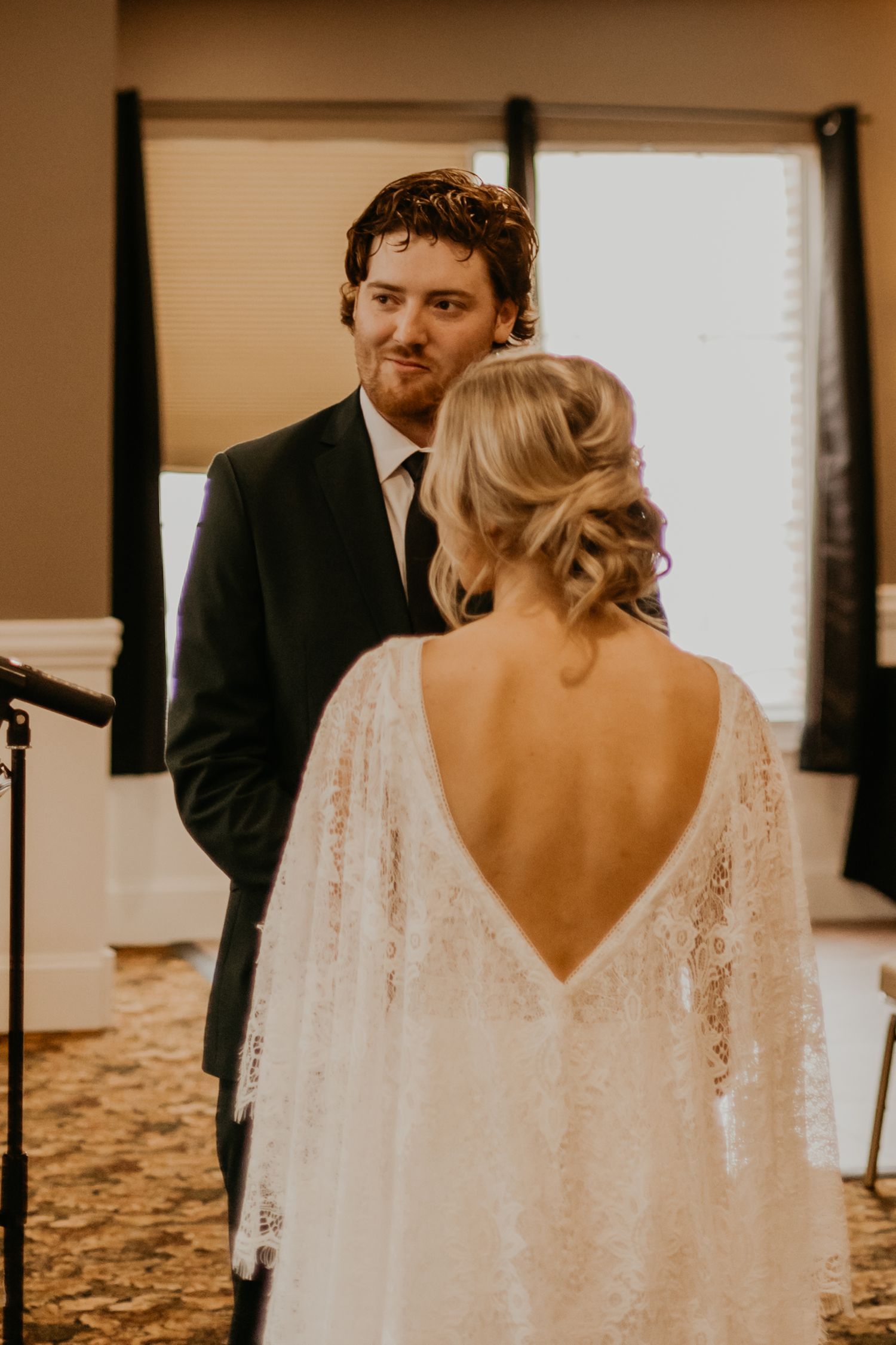 Couple shares intimate moment during first look at indoor wedding ceremony.