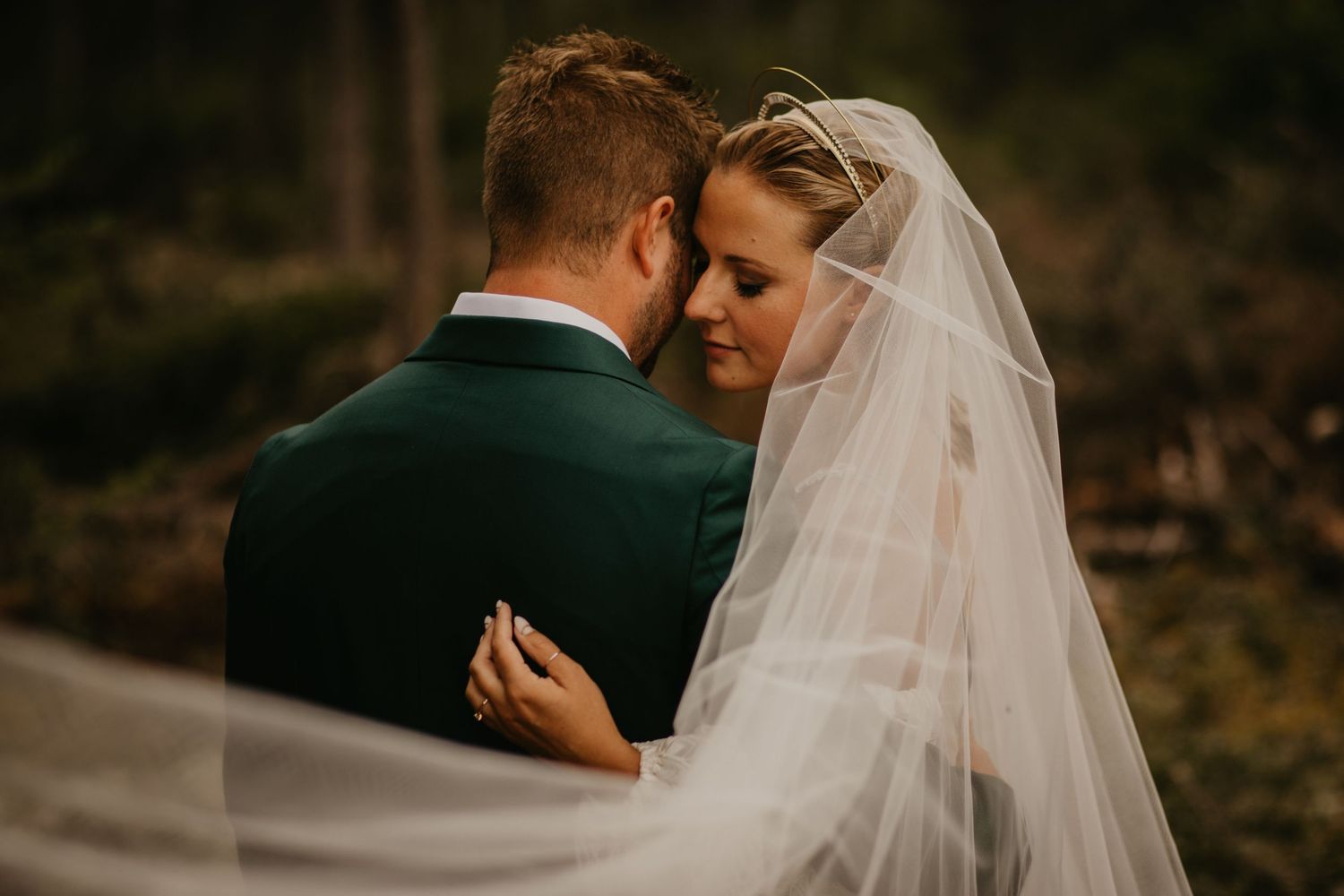 Tender embrace captured during outdoor forest wedding ceremony.