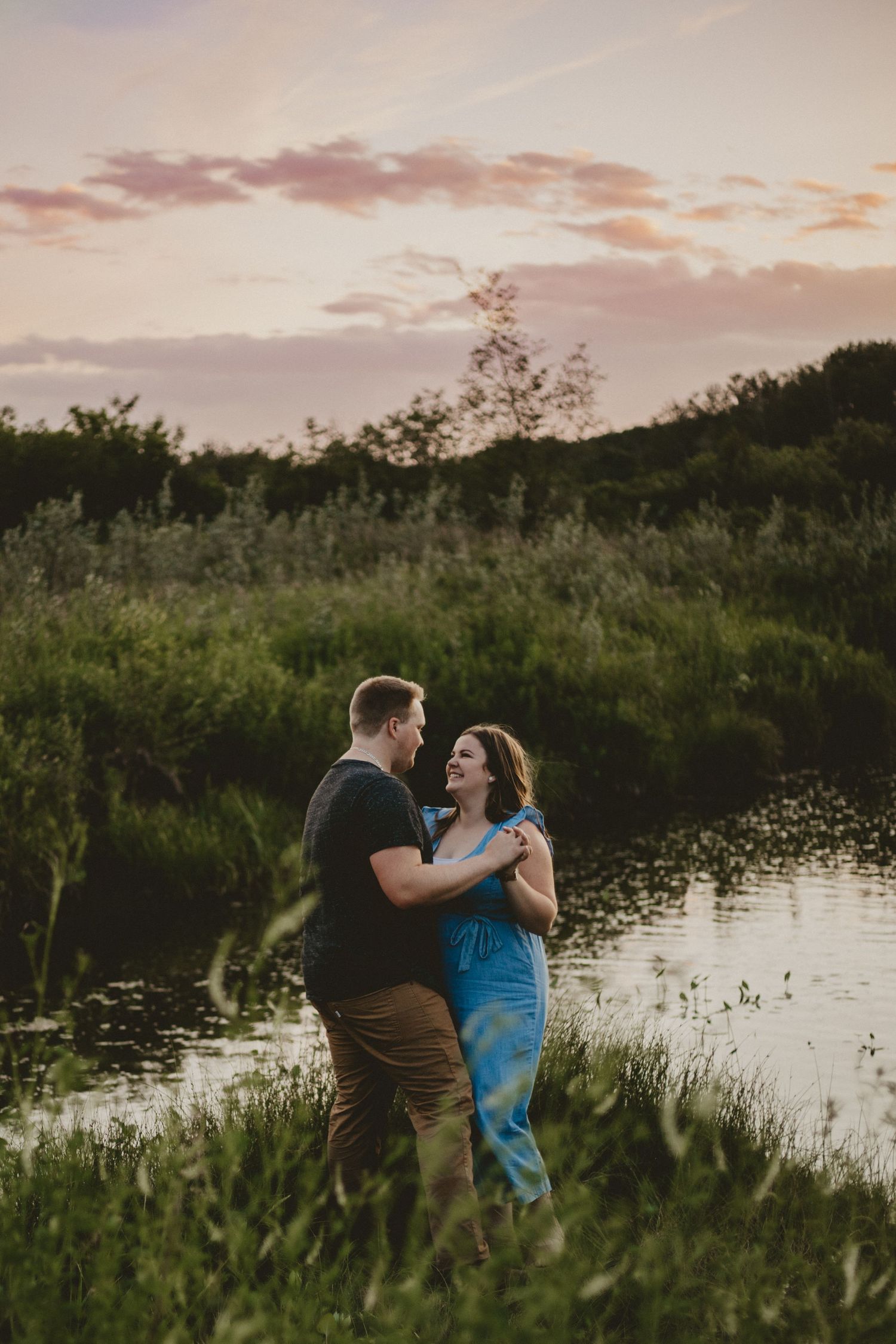 Couple dancing together by a lake during sunset.