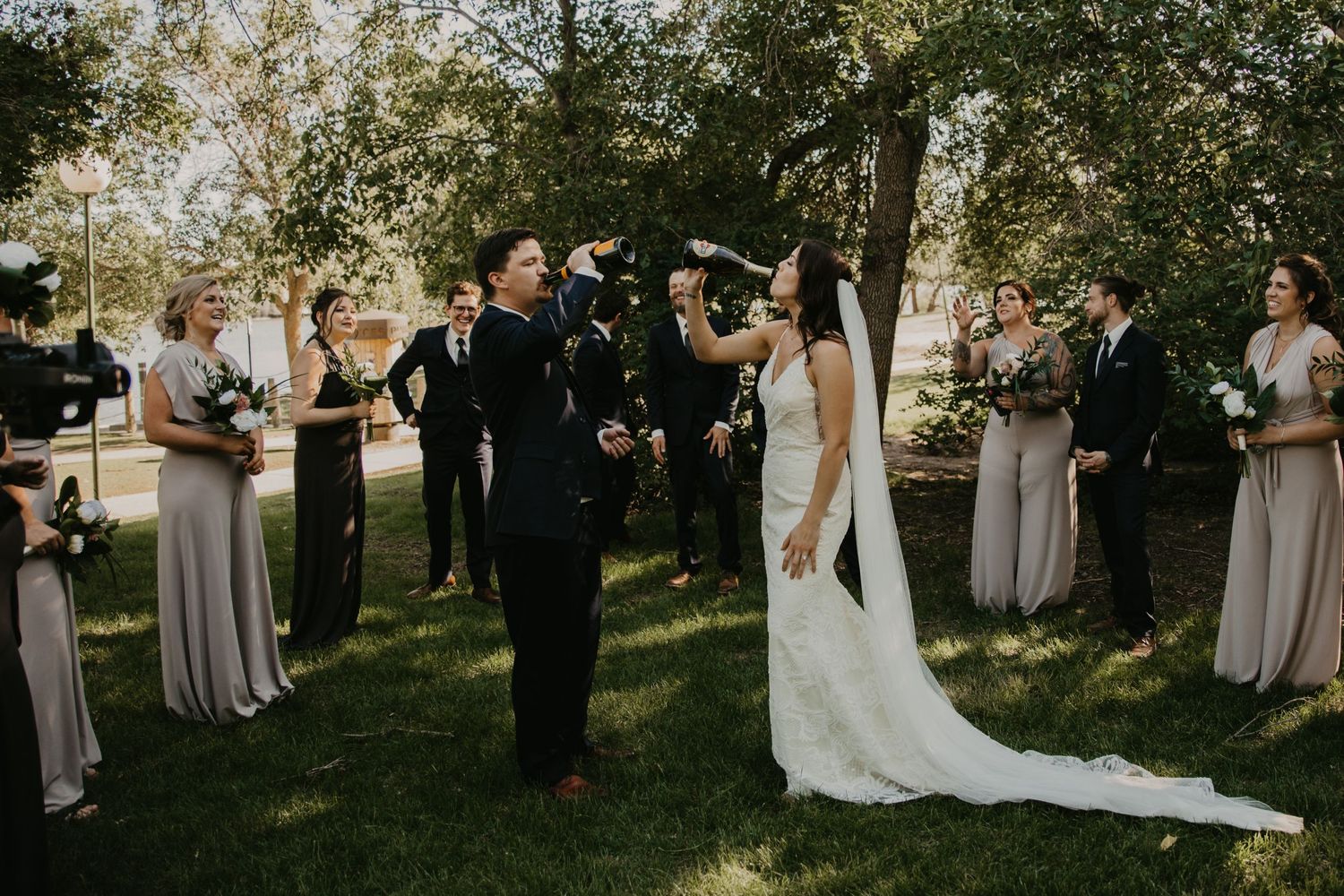 Outdoor wedding ceremony with wedding party gathered on sunlit lawn.
