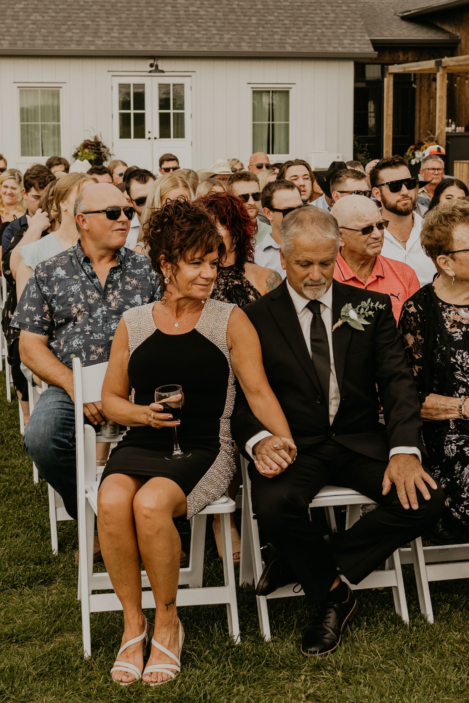 Wedding guests seated in formal attire during an outdoor ceremony.