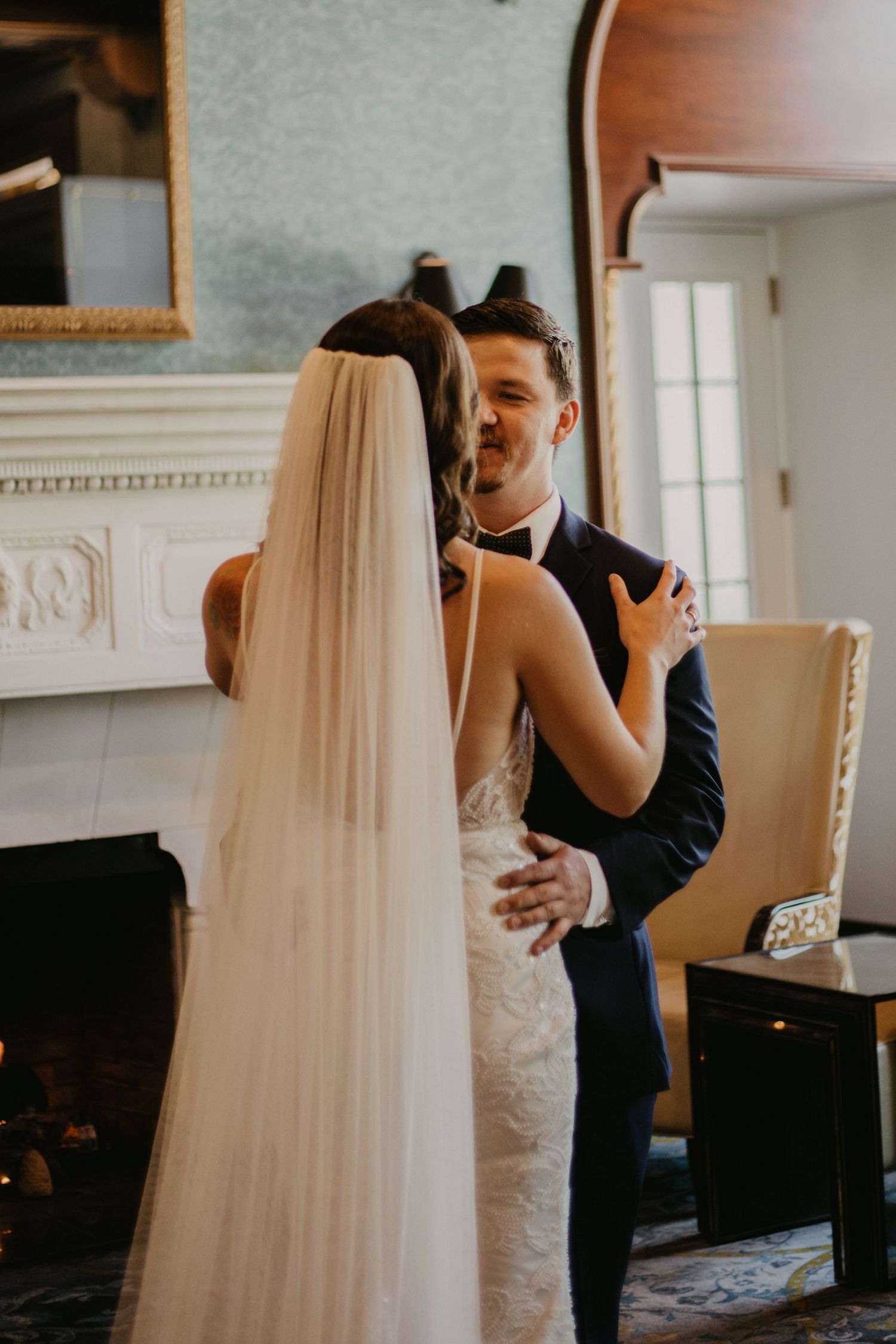 A joyful first look wedding moment captured in a room with classic architectural details.