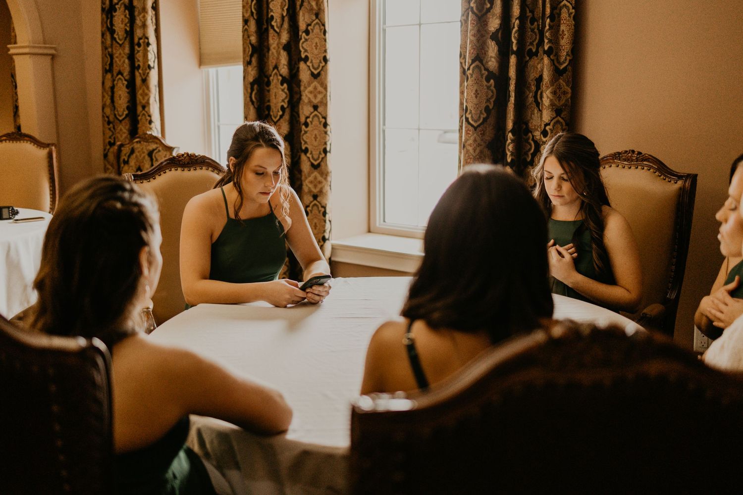 A group gathers around a table in formal attire during a wedding celebration.