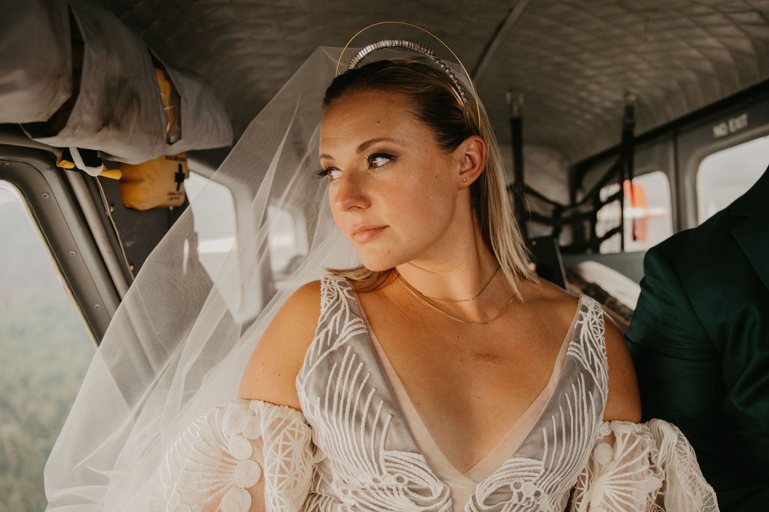 Interior shot of bride in lace dress with veil sitting in aircraft.