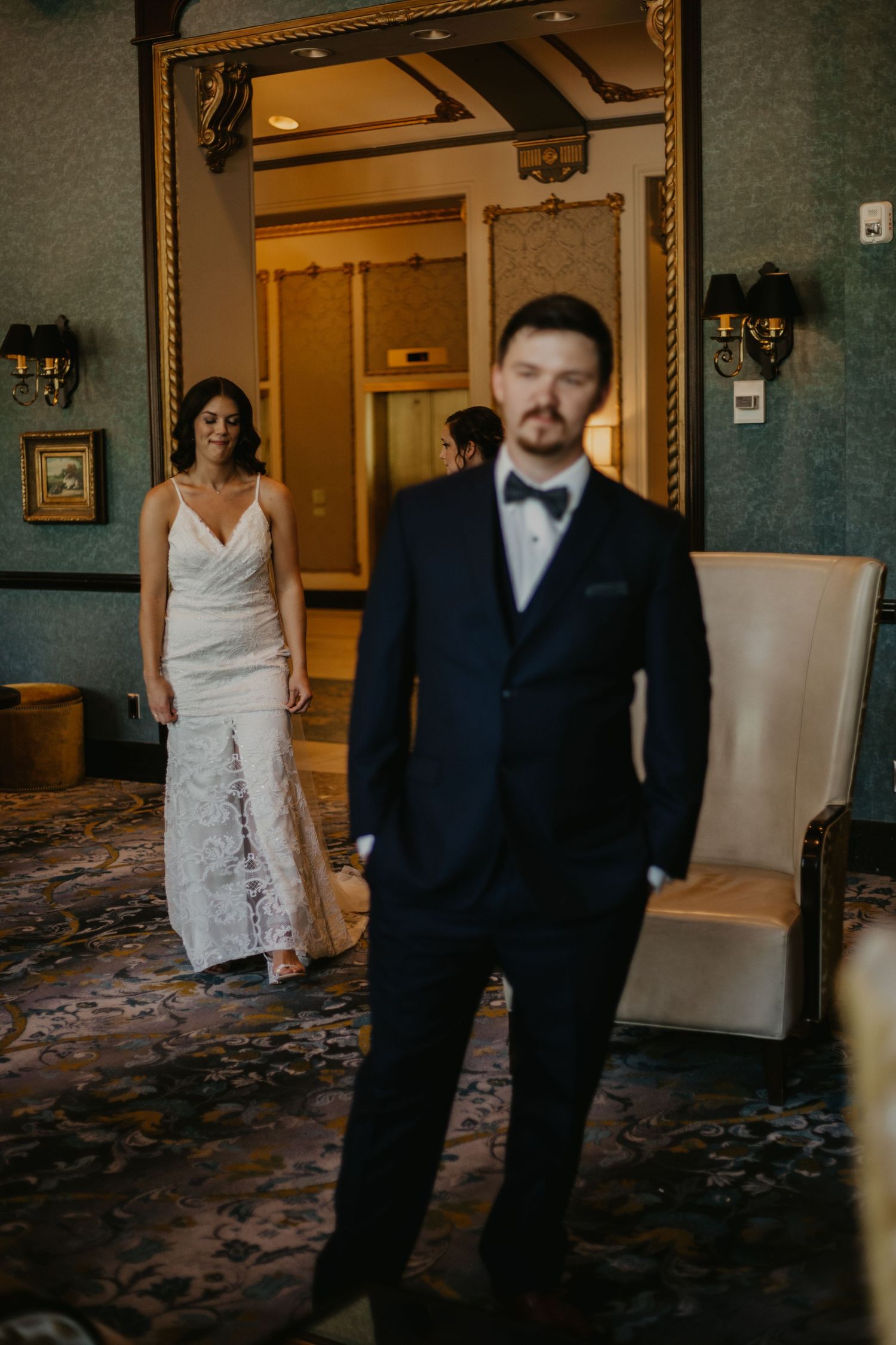 An artistic wedding photo showing the couple's first look in a vintage-styled room.