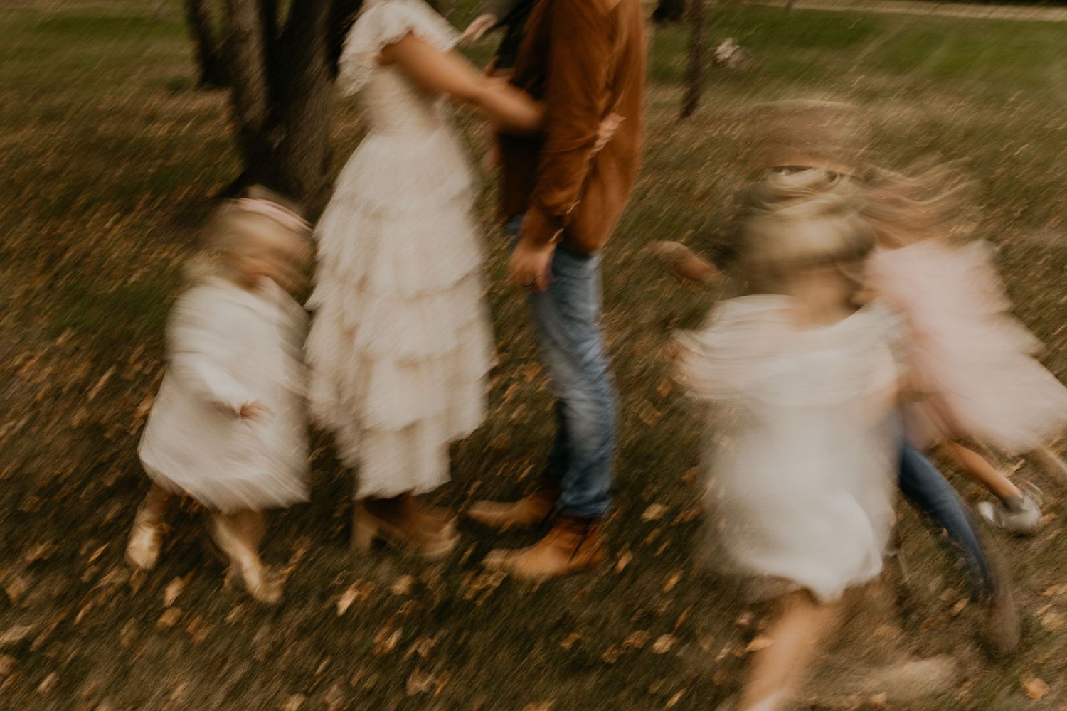 Motion-blurred photo of people dancing in white dresses outdoors.
