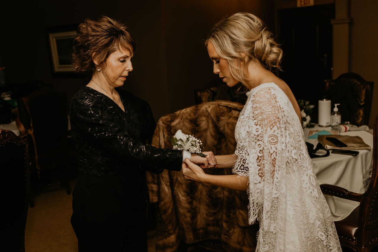 Two people examining a fur stole during wedding preparations in warm lighting.