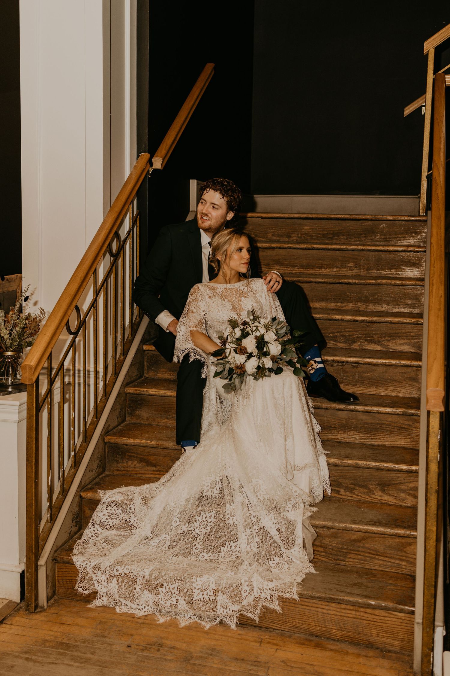 Romantic wedding portrait on vintage wooden staircase with flowing lace train.