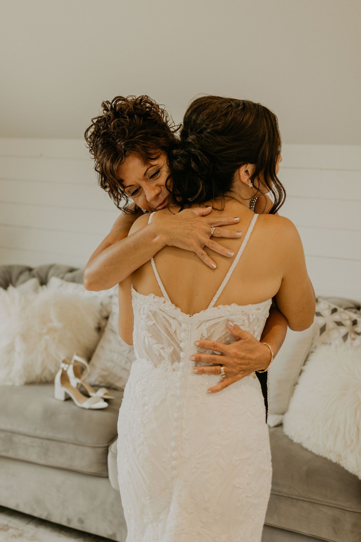 An emotional embrace captured in soft lighting against a cream-colored sofa.