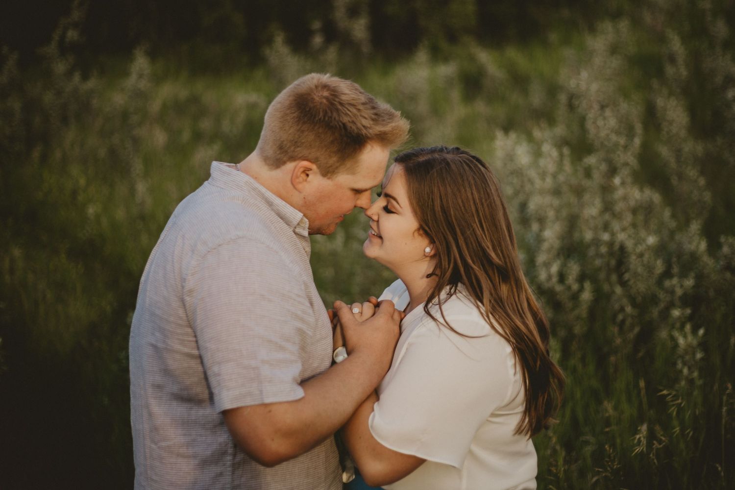 A tender embrace captured during an outdoor couples photoshoot in tall grass.