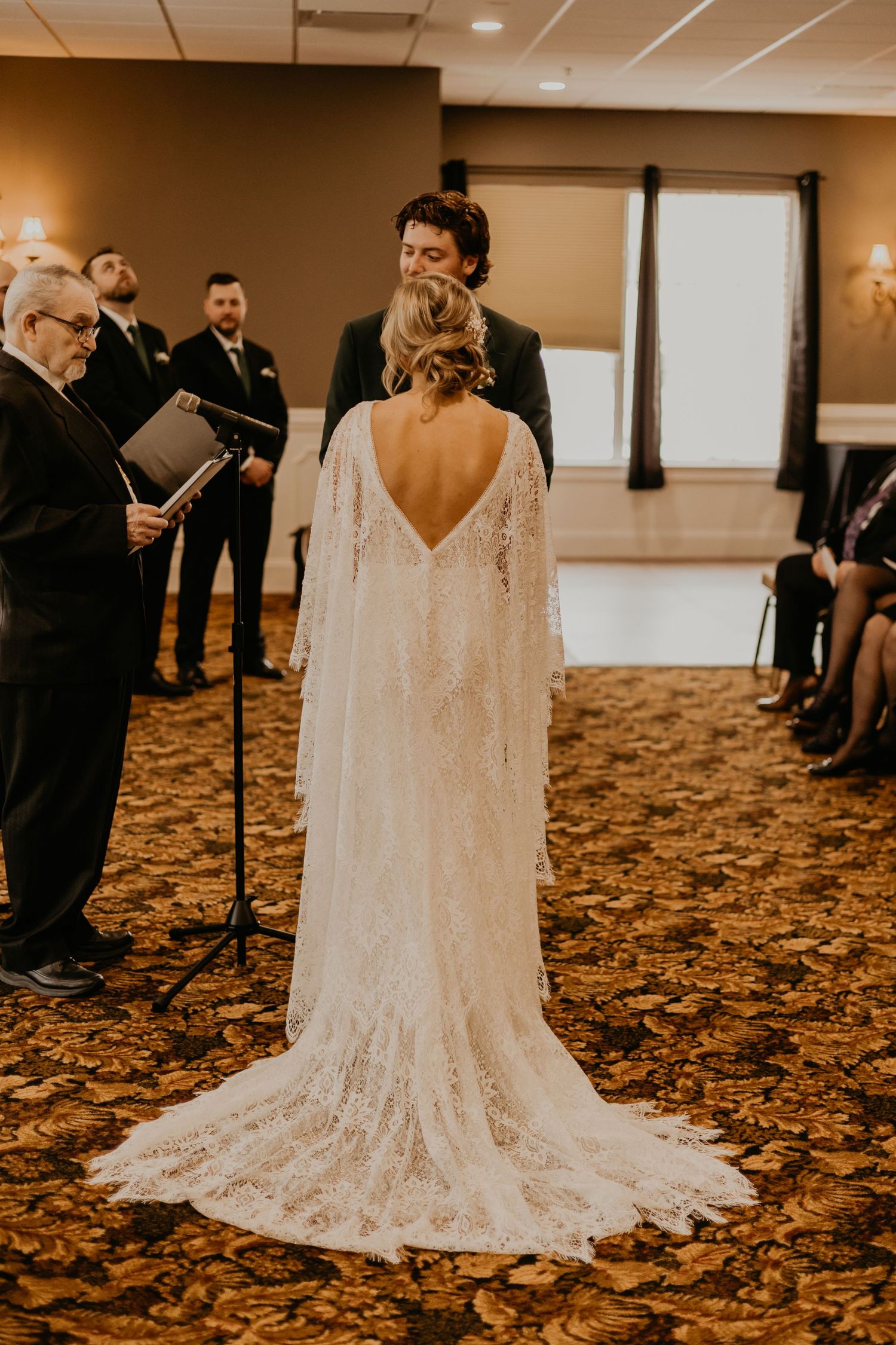 Wedding ceremony showing back of bride's lace dress with long train.