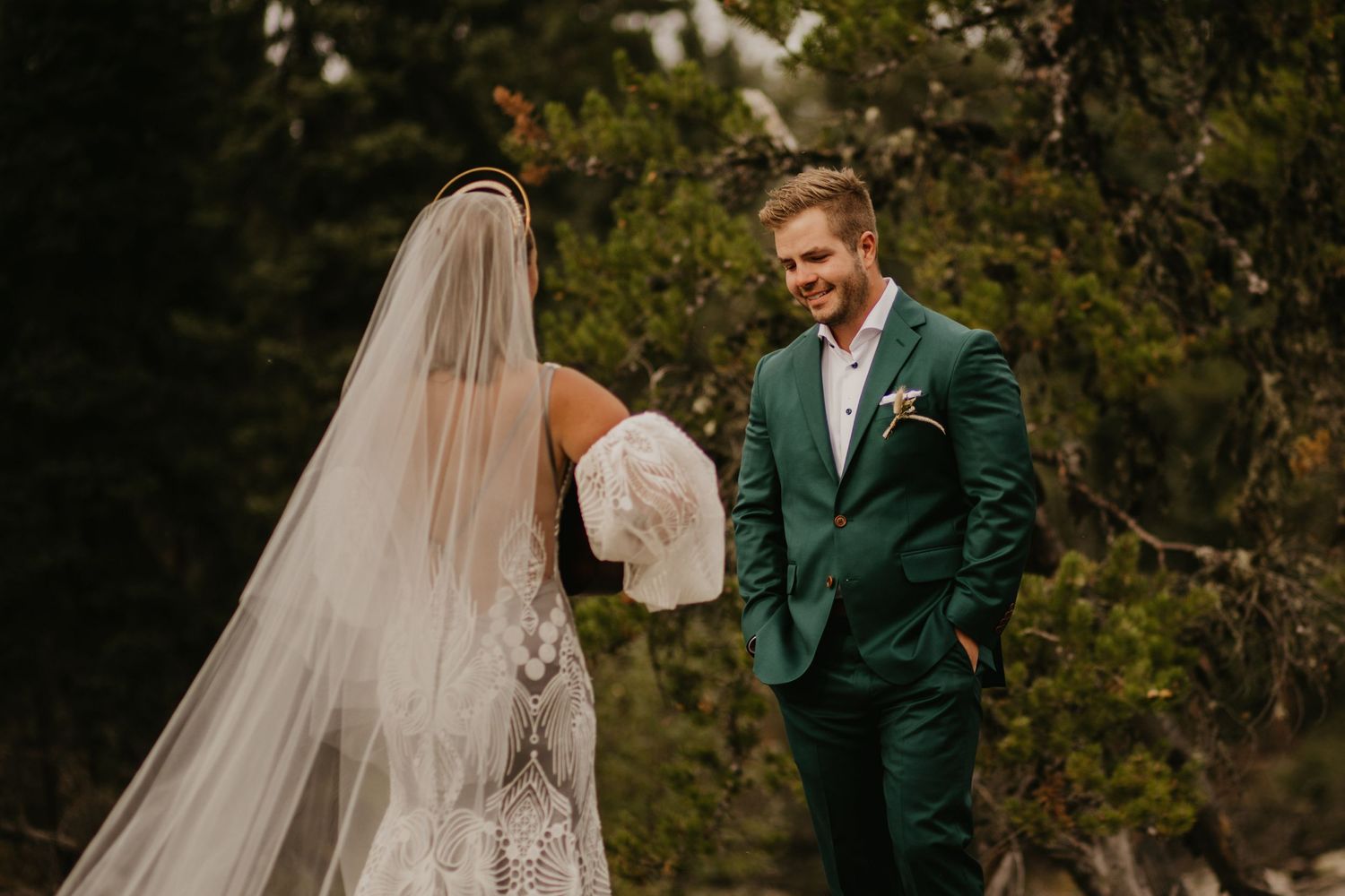 Intimate first look wedding moment surrounded by lush greenery and trees.