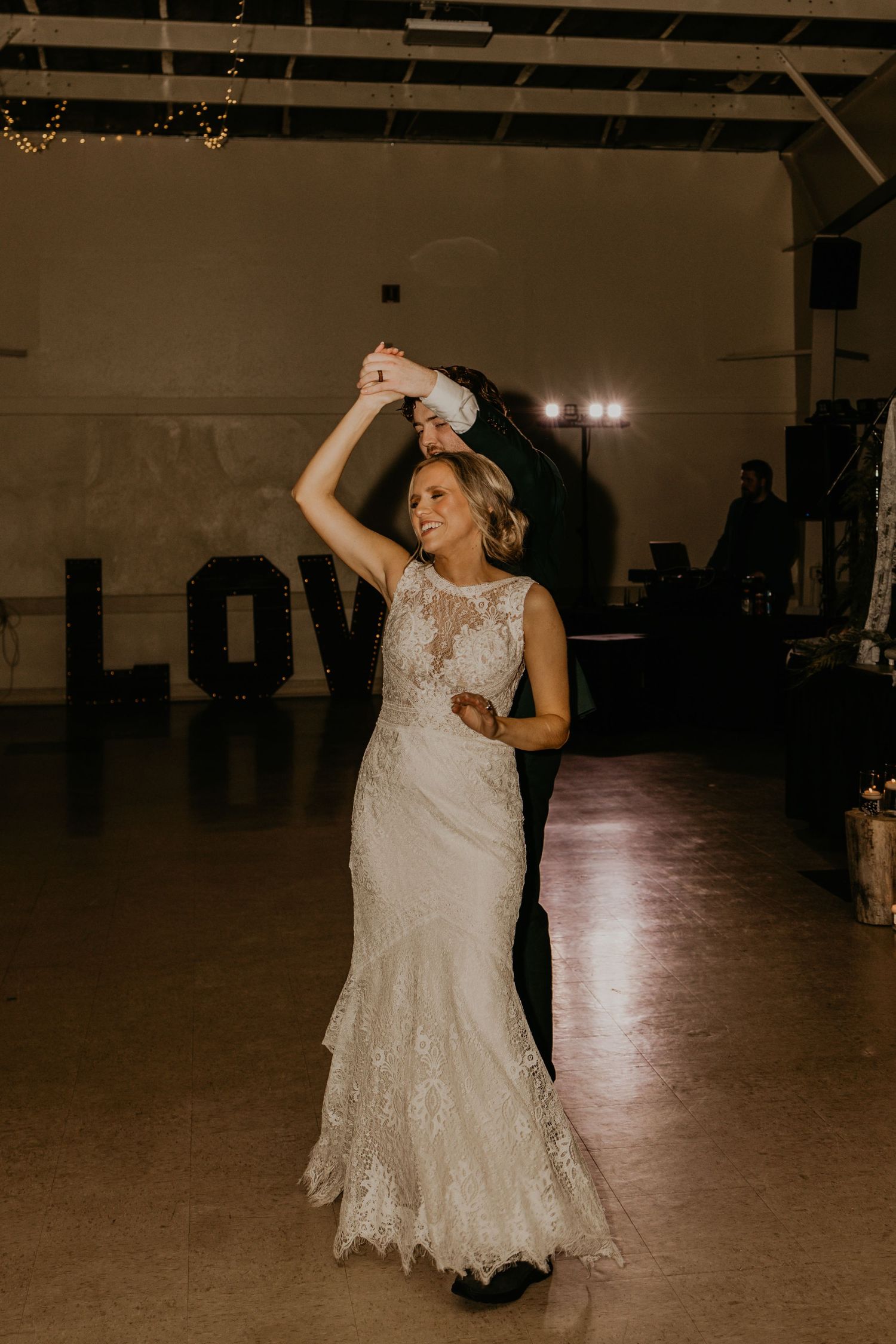 A joyful spin during a wedding dance with a lace gown flowing in an elegant reception space.