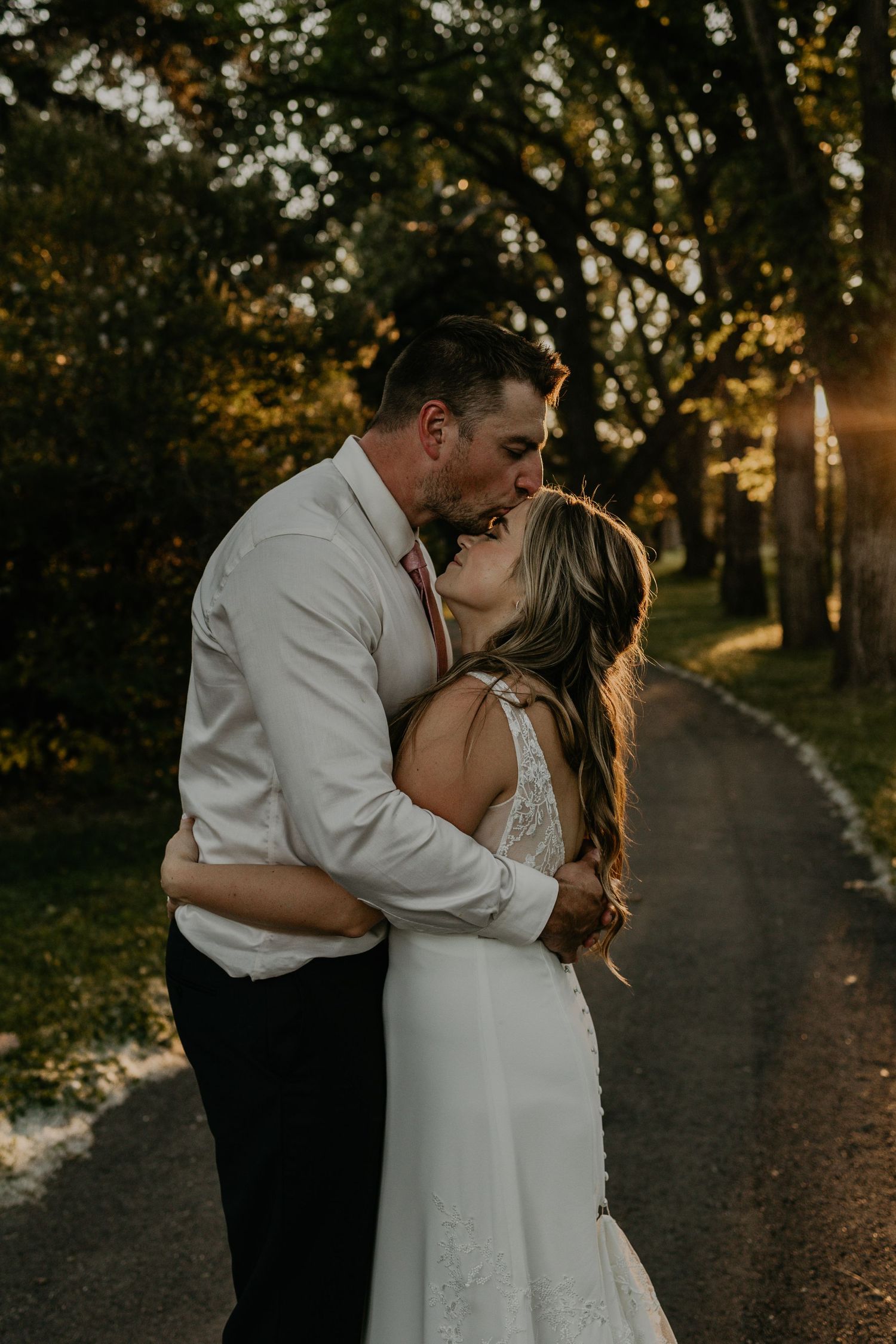 Intimate moment between couple during sunset on wooded path.